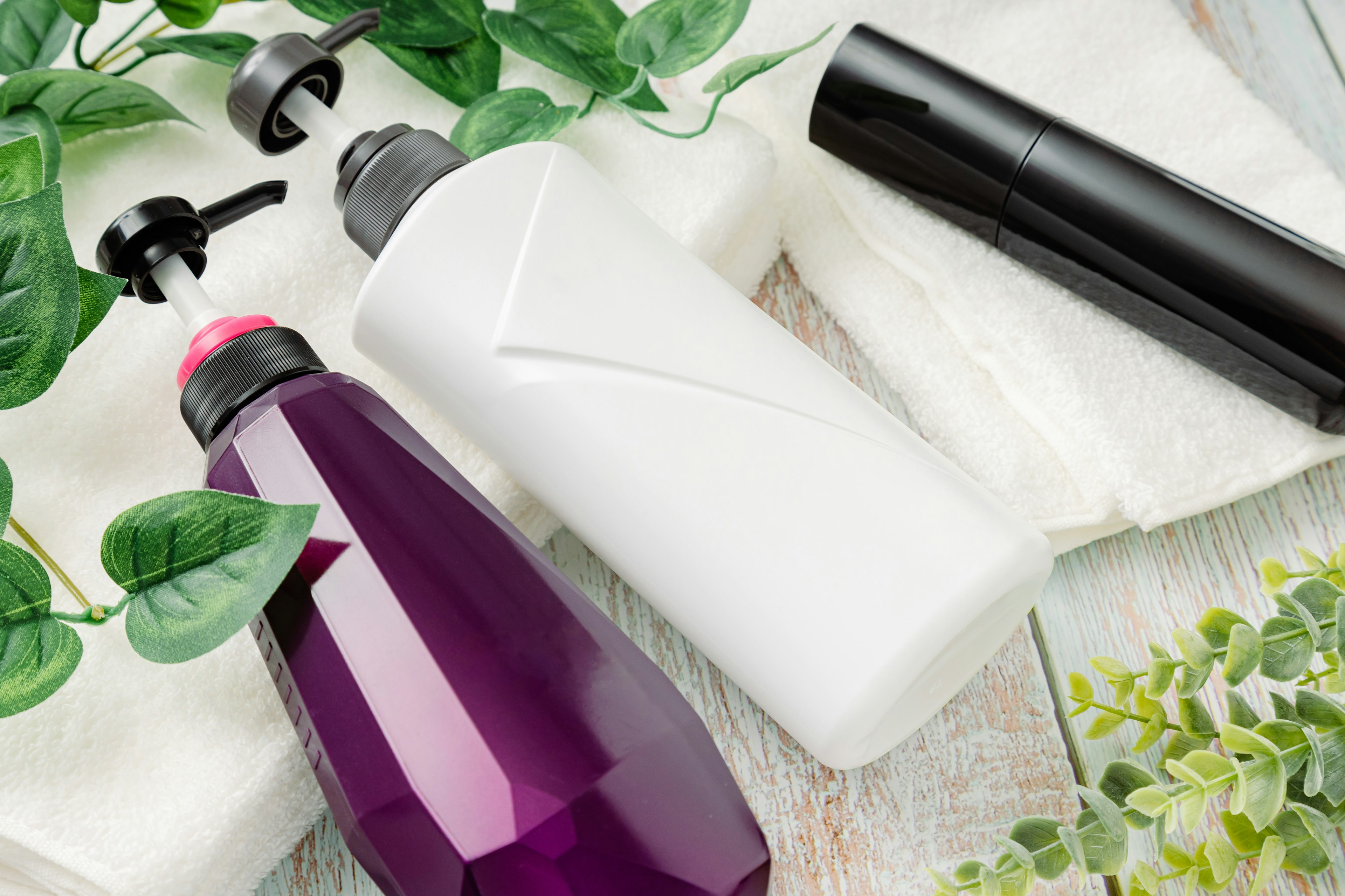 Purple and white bottles placed with green plants on a wooden surface