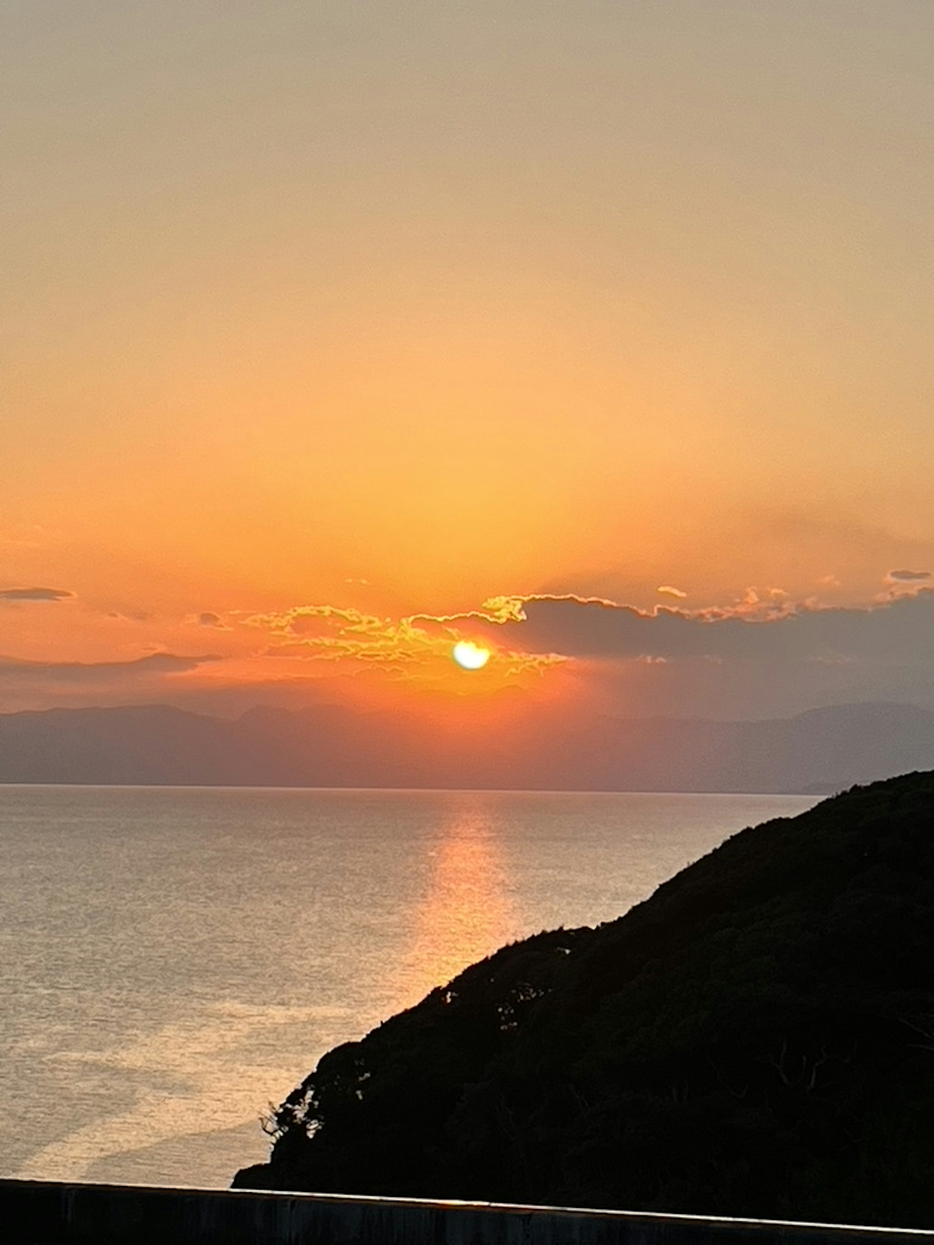 Schöner Sonnenuntergang über dem Ozean mit der Silhouette eines Hügels