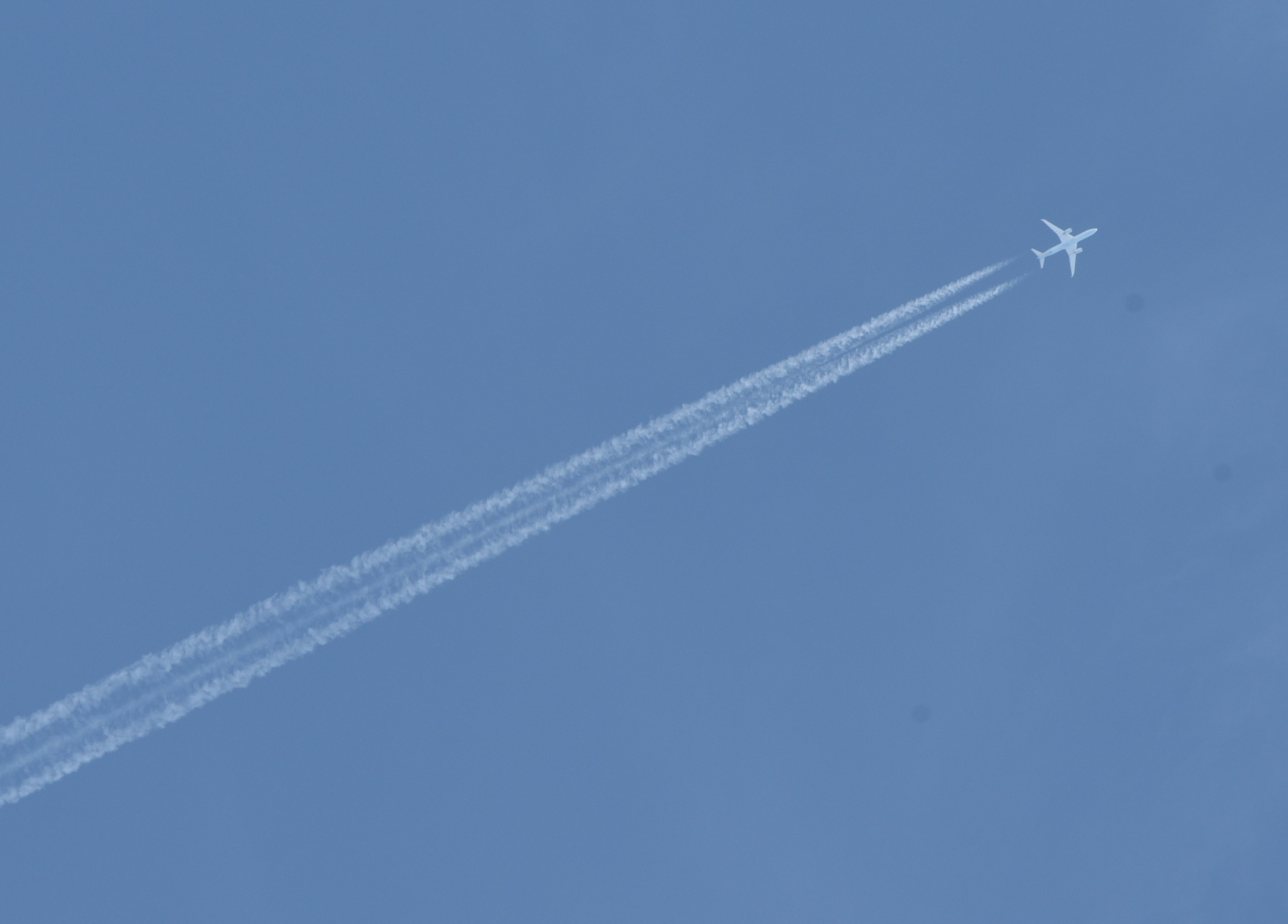 Airplane flying in a blue sky with contrails