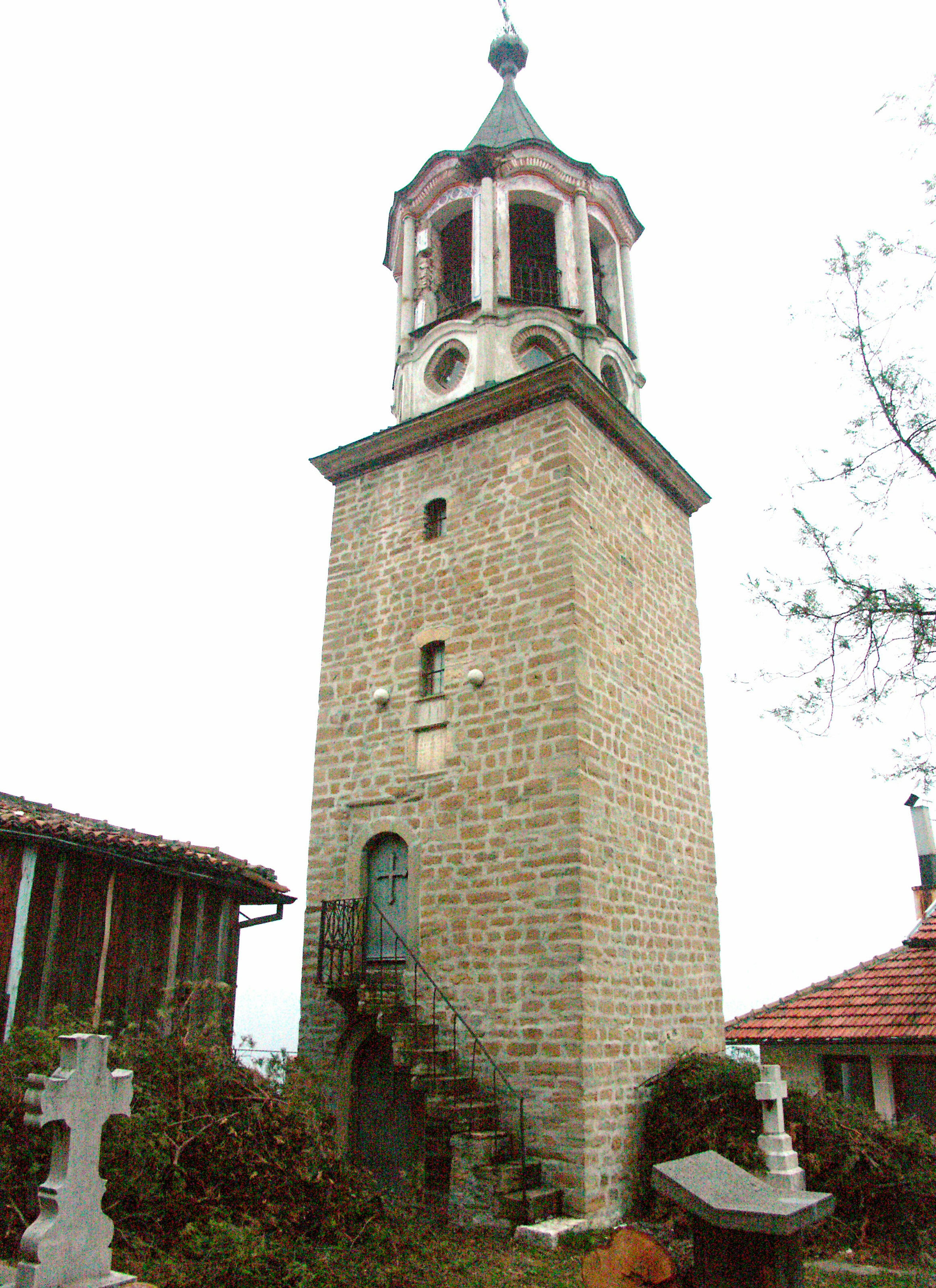 Old stone bell tower with stairs near a church