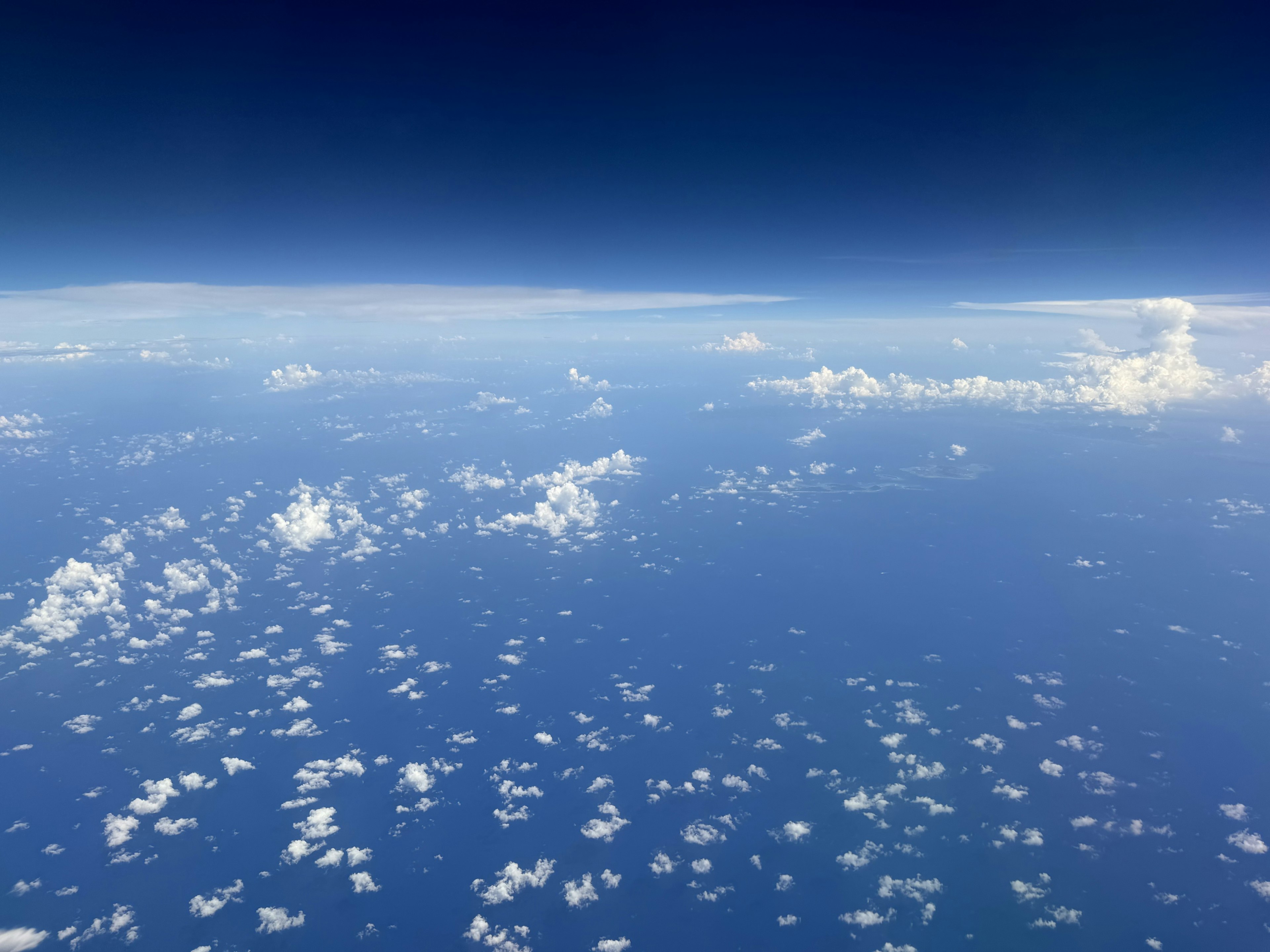 Vista aérea del océano azul y nubes blancas bajo un cielo despejado