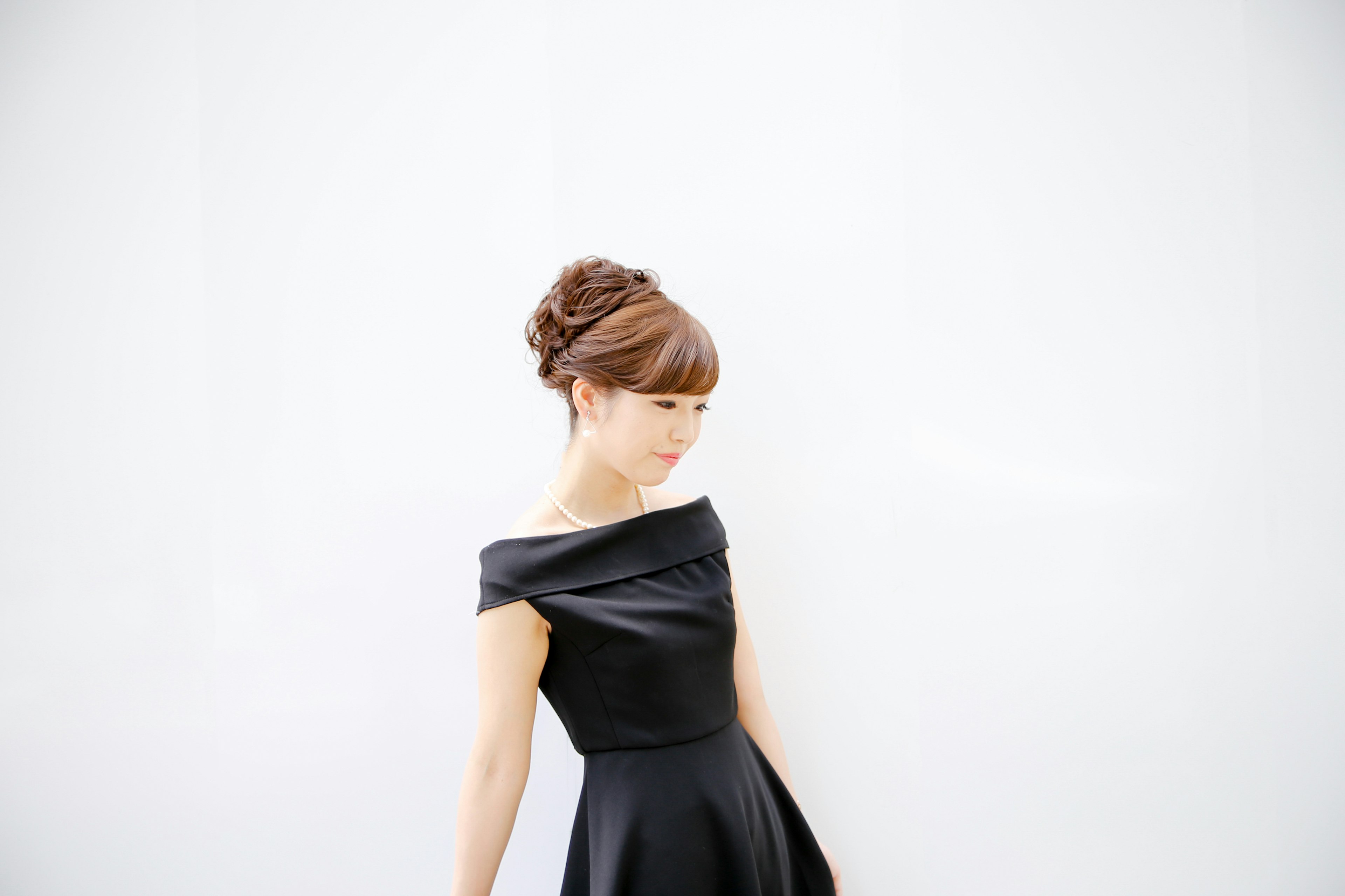 A woman in a black dress turning sideways against a white background