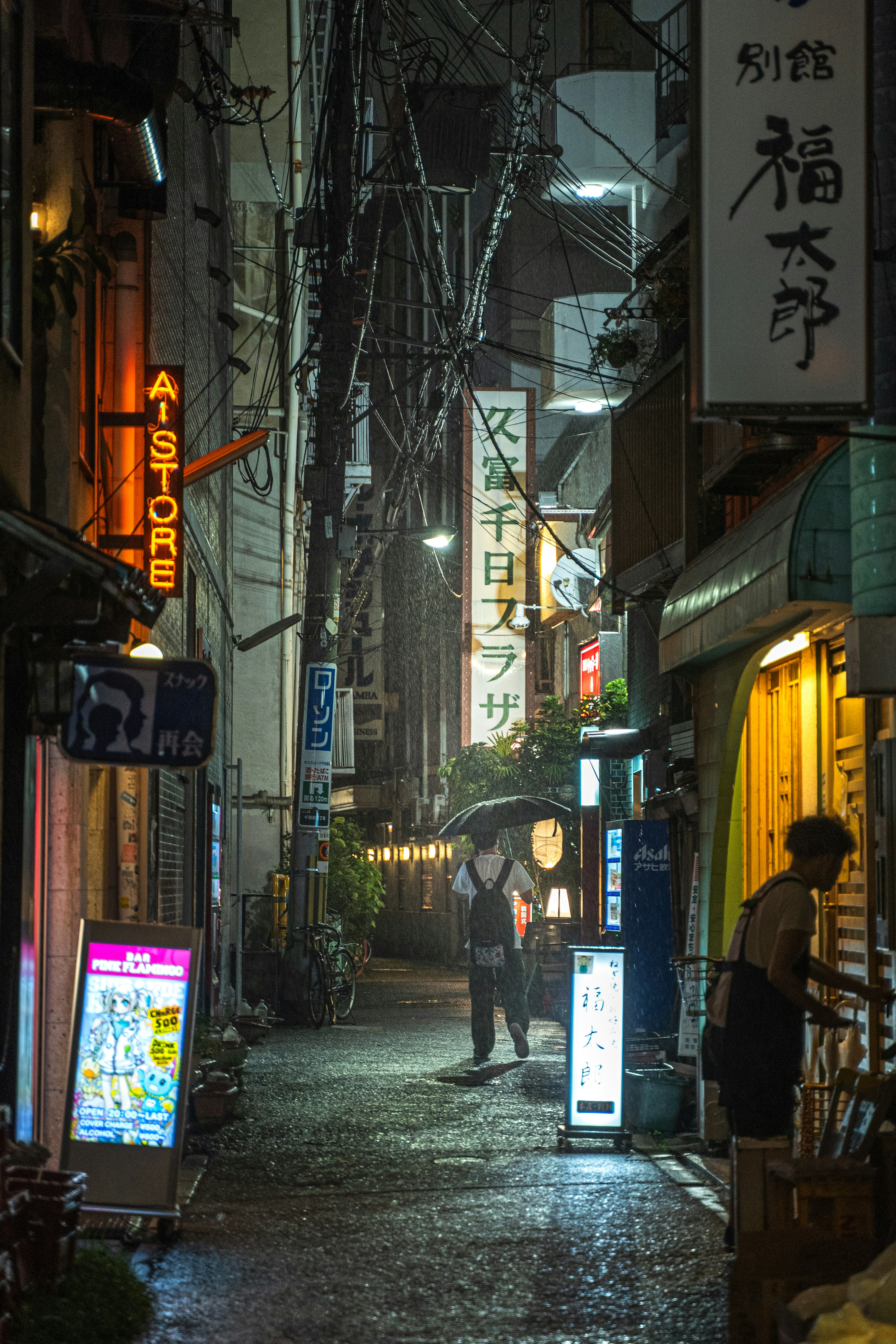 Ruelle étroite éclairée par des enseignes de restaurants la nuit