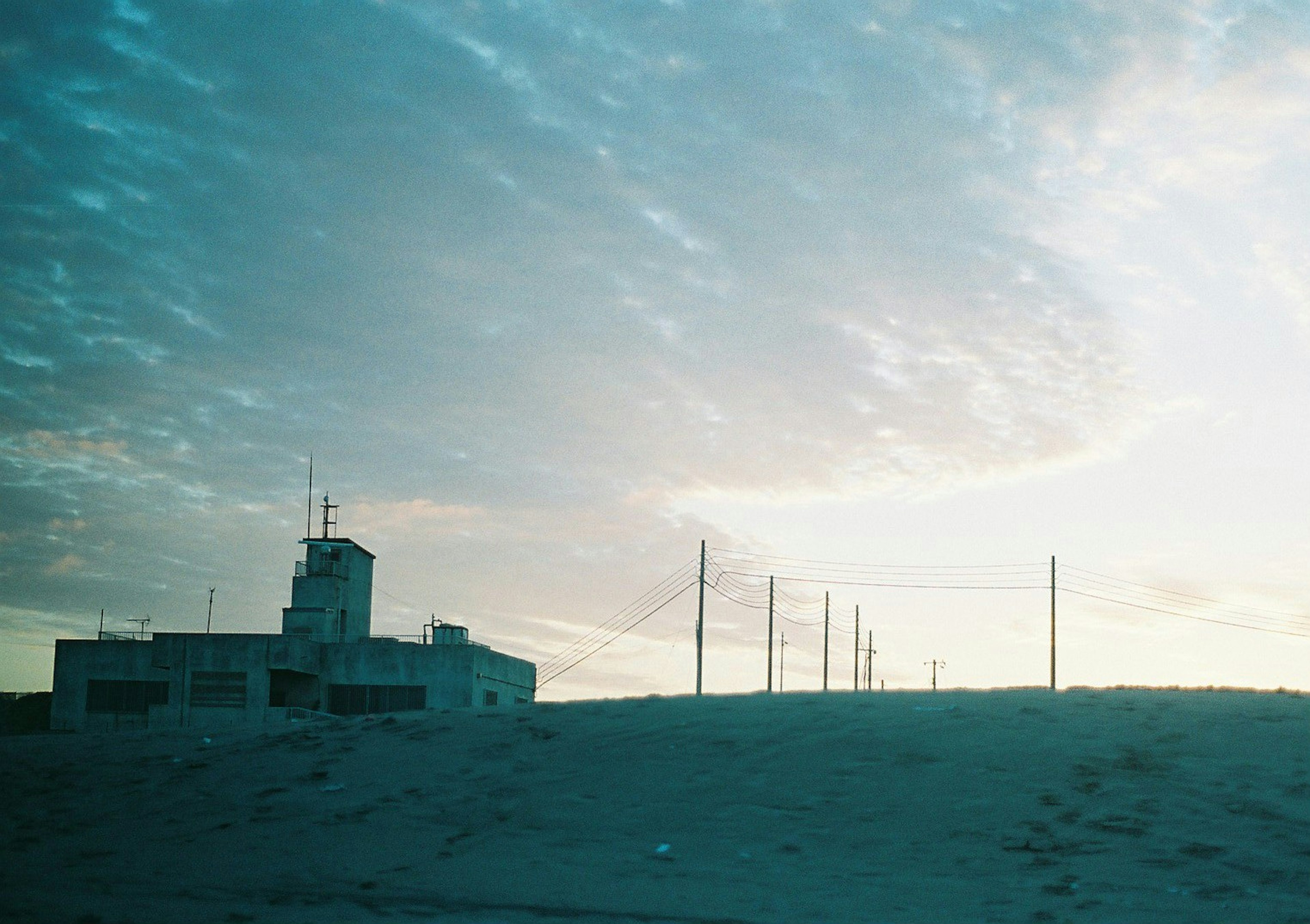 Isolated building and power lines against a sunset sky