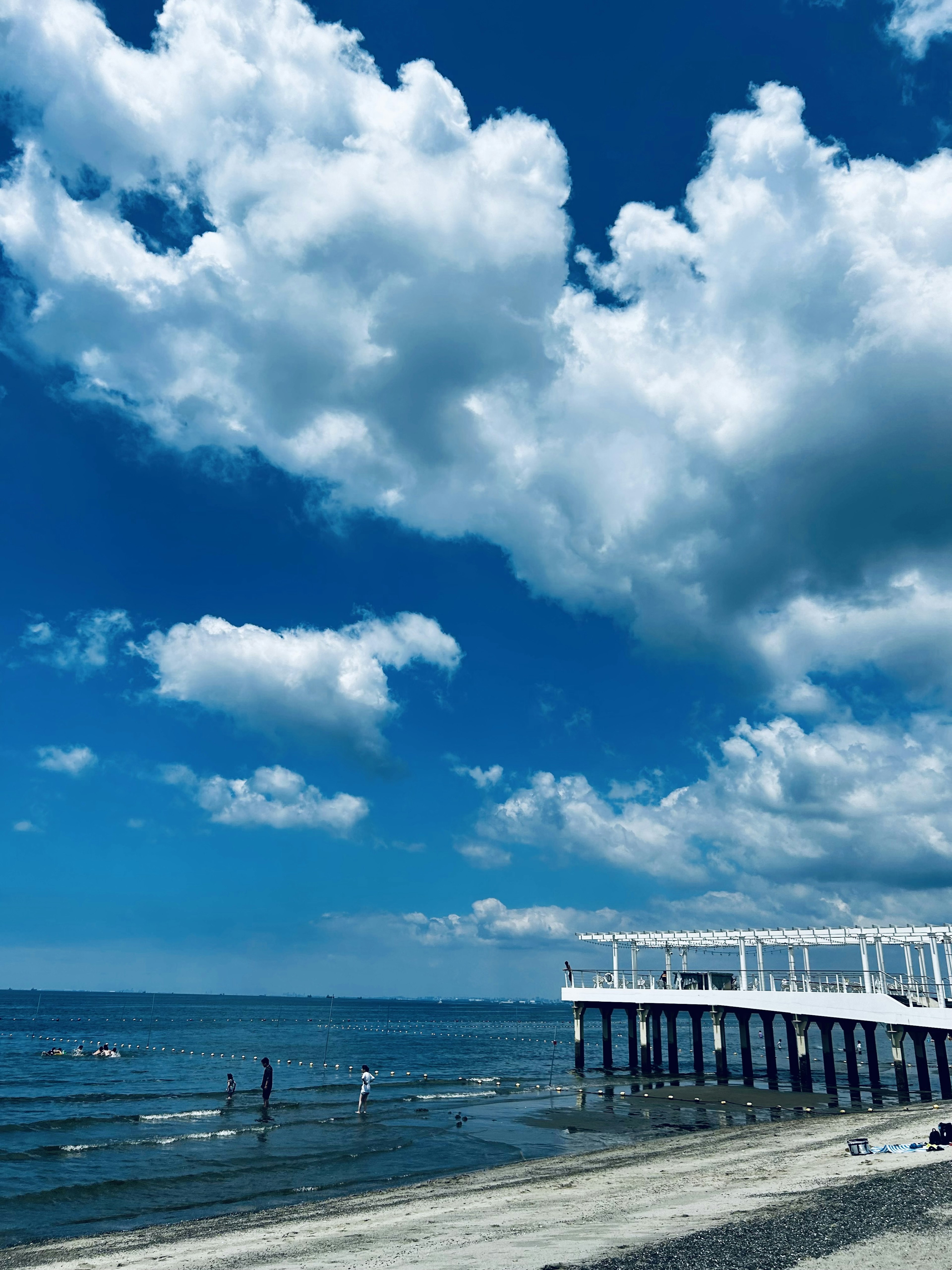 Scena costiera con cielo blu e nuvole bianche un molo in legno che si estende sull'acqua