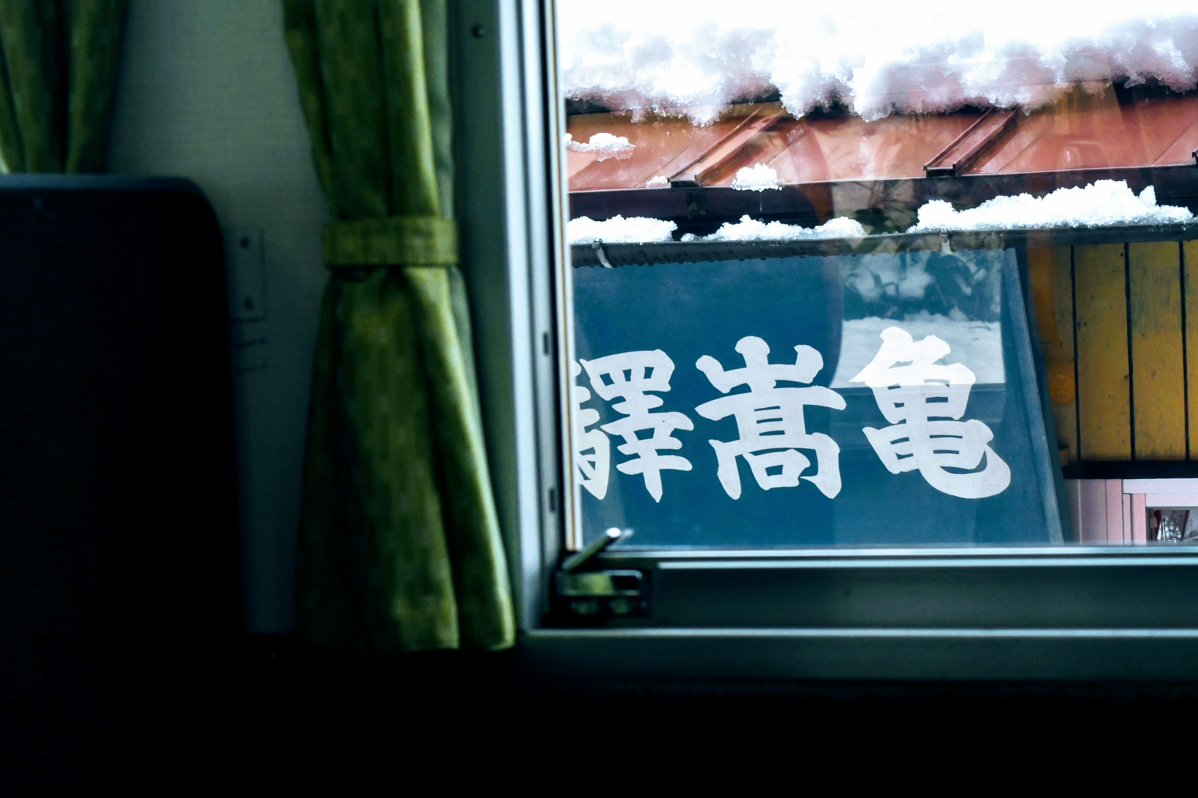 View from a window showing a snowy roof and a sign