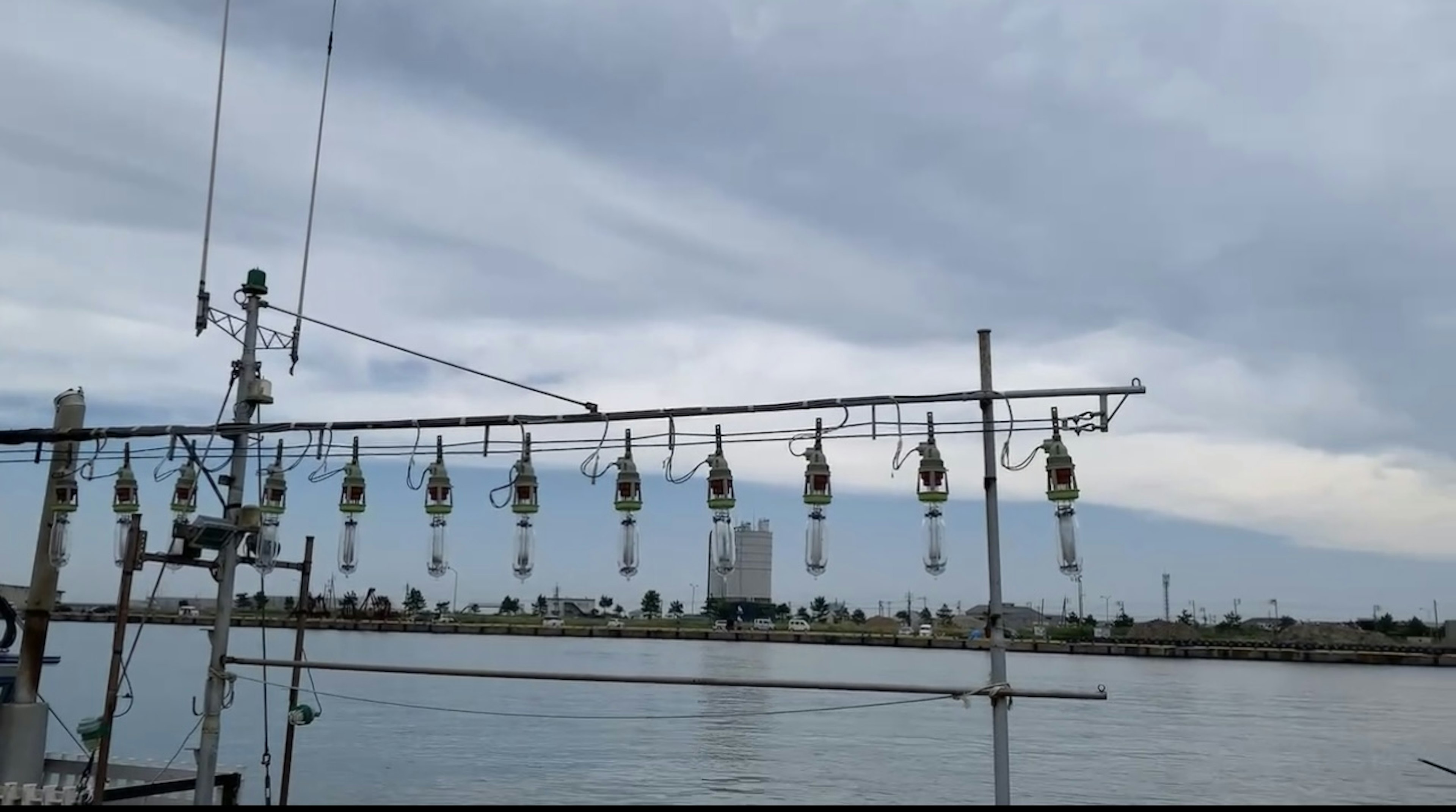 Eine Ansicht des Wassers, das einen bewölkten Himmel mit einem langen Angelrutenaufbau spiegelt