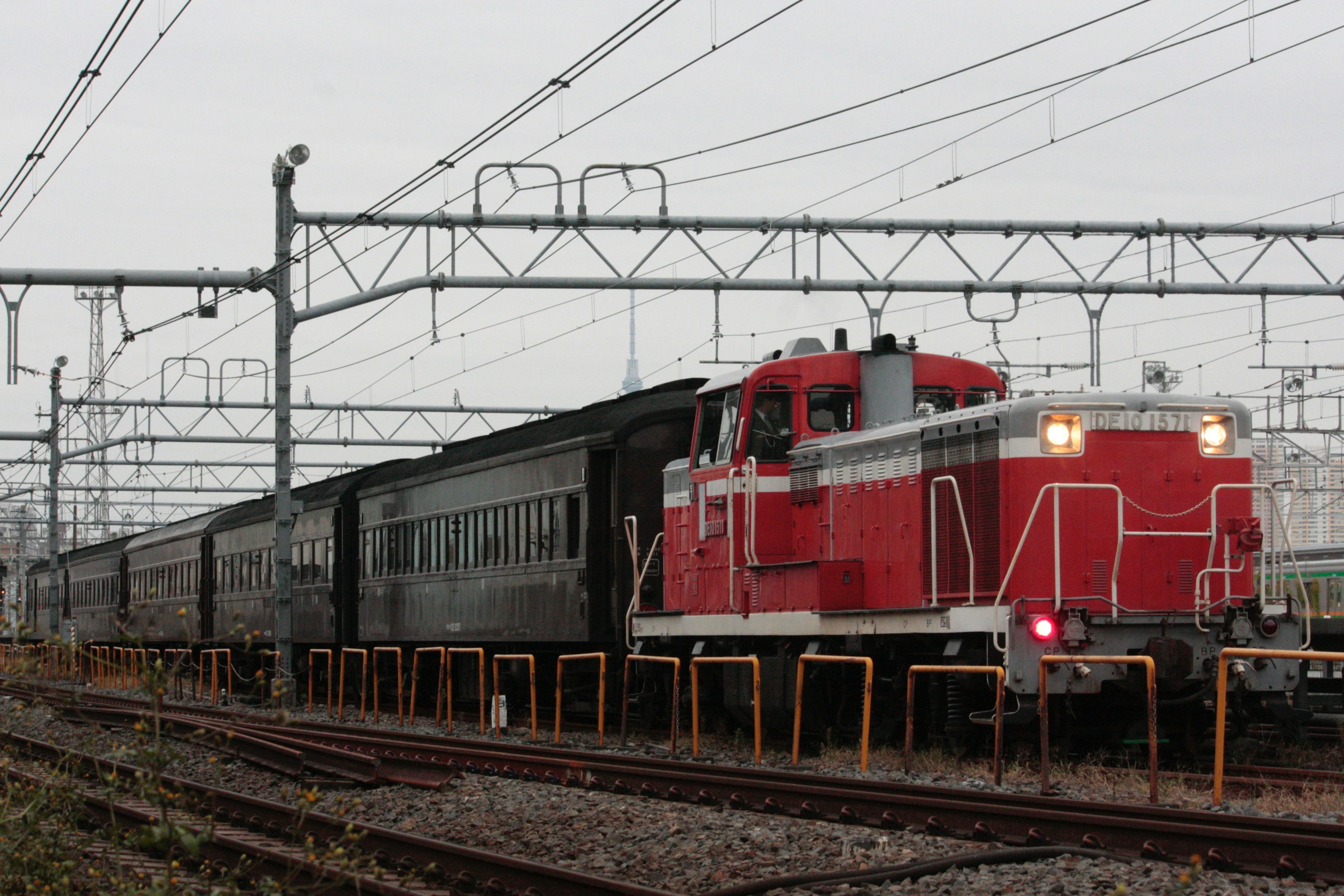 Rote Lokomotive mit schwarzen Personenwagen in einer Eisenbahnumgebung