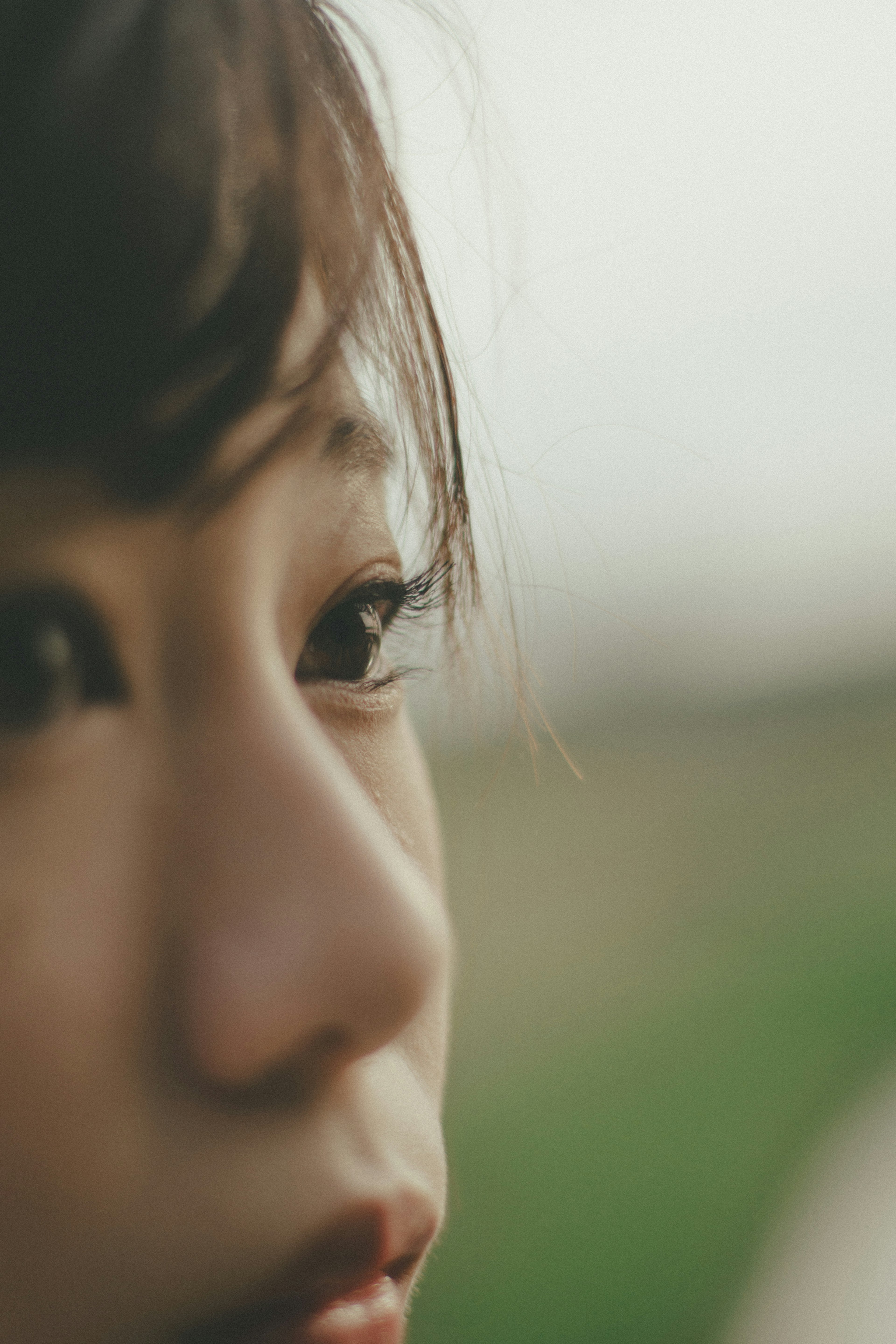 Close-up of a woman's face with striking eyes and a serene expression, blurred green background