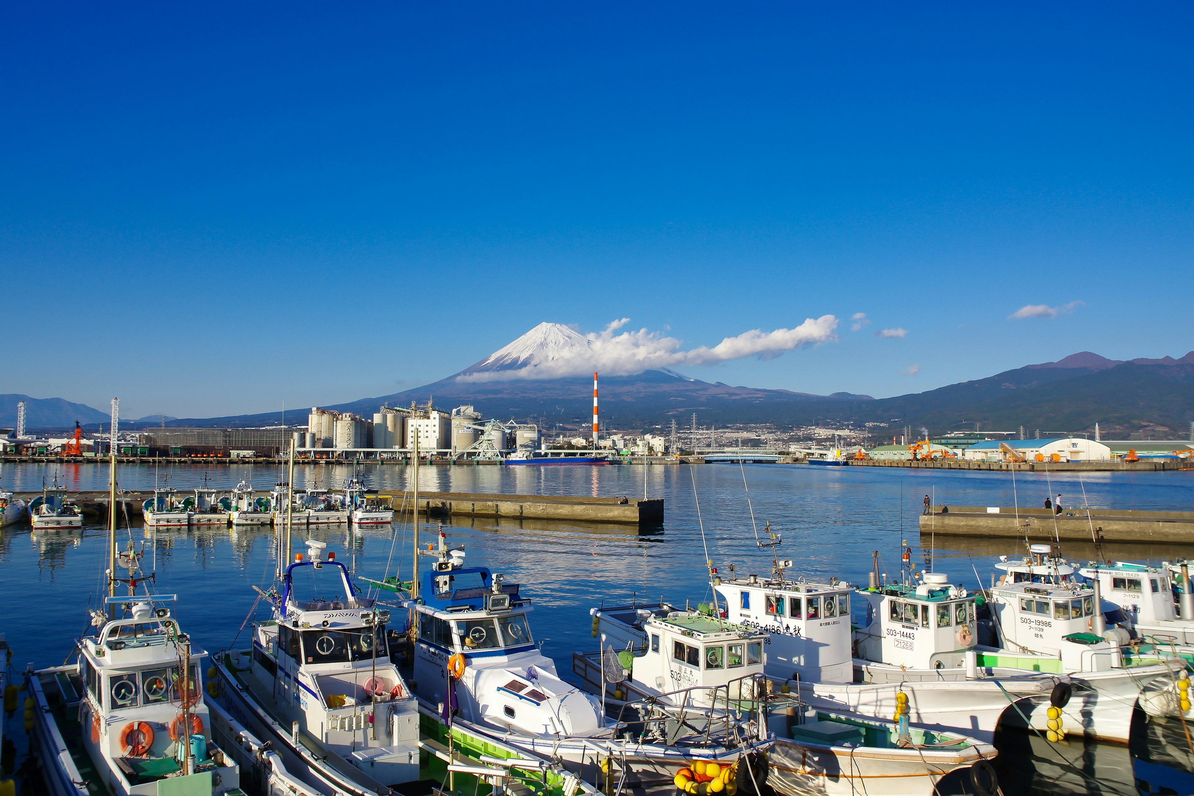 静かな港に停泊する漁船と富士山の美しい風景