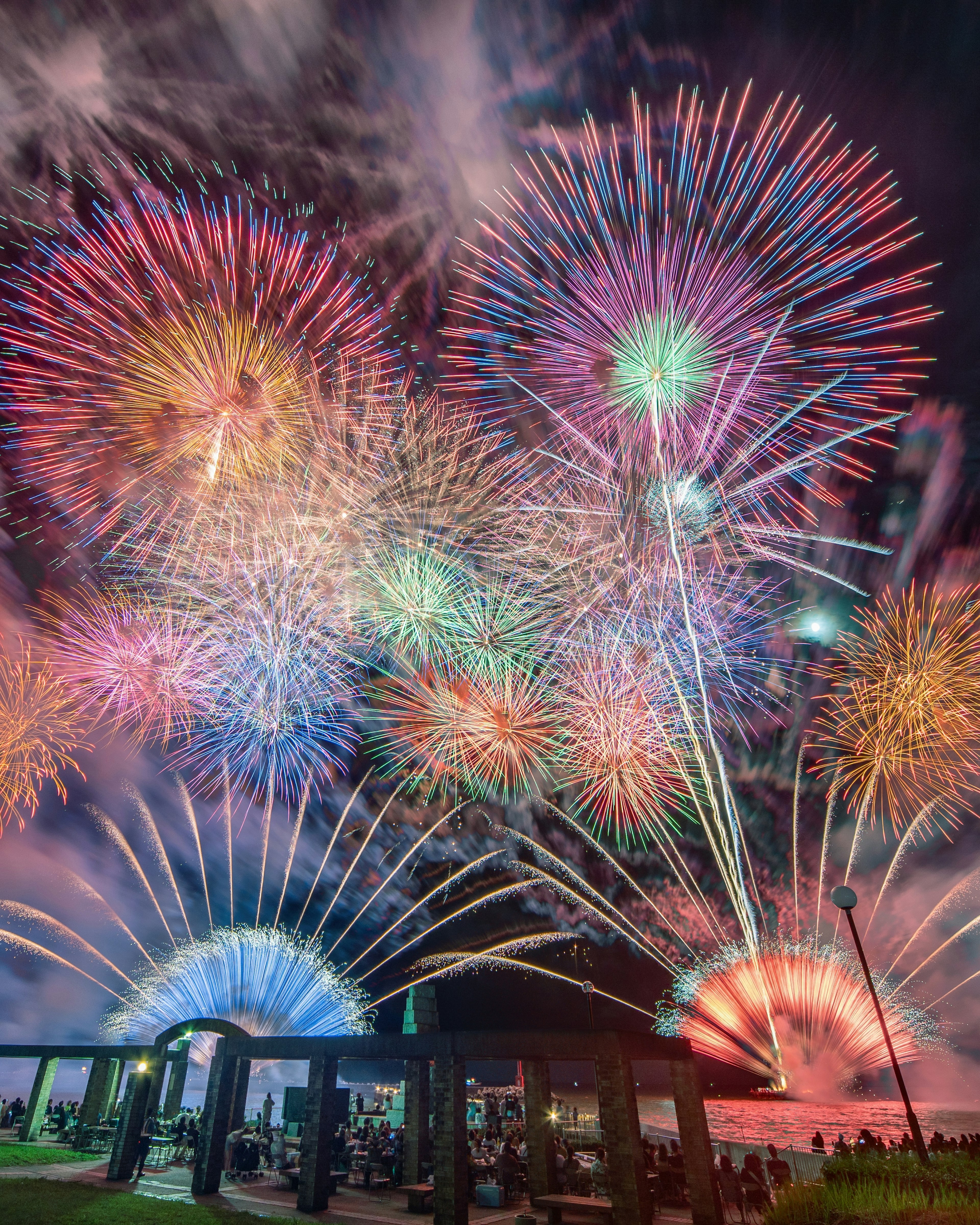 Bunte Feuerwerke, die am Nachthimmel über einer silhouettierten Struktur explodieren