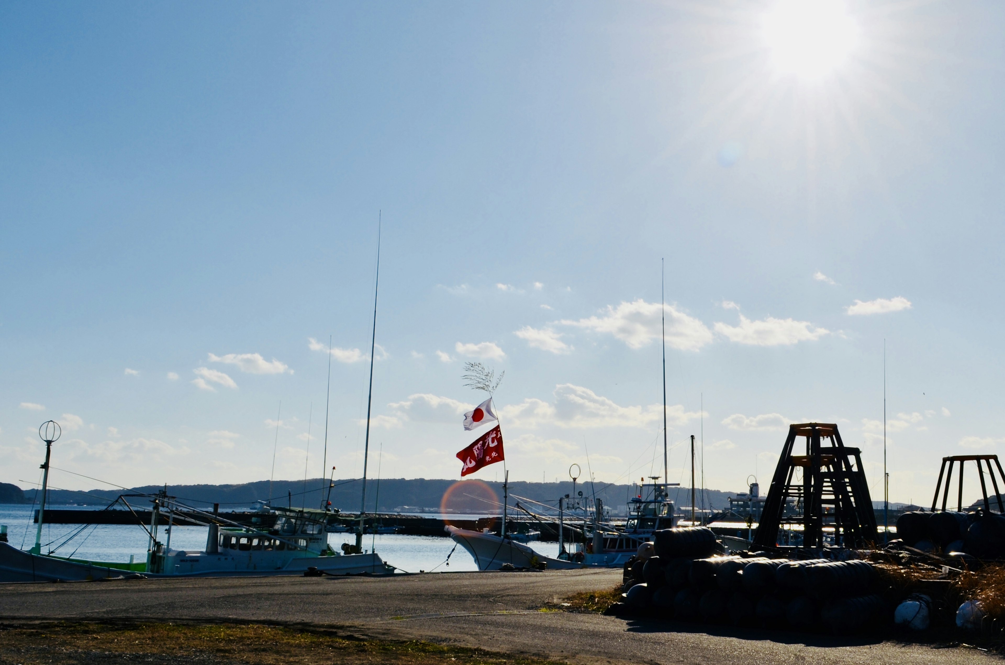 Boats docked under a bright sky with a visible flag