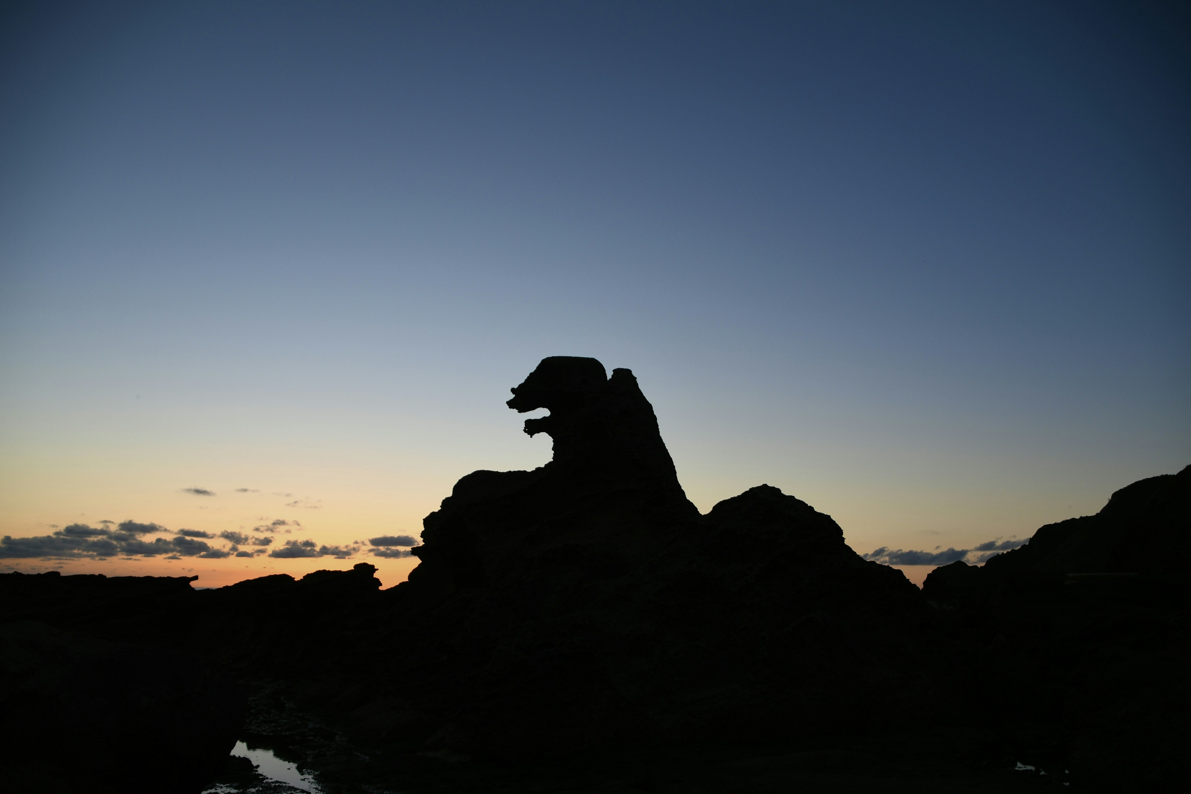 Silhouette di una roccia che assomiglia a un leone contro un cielo crepuscolare