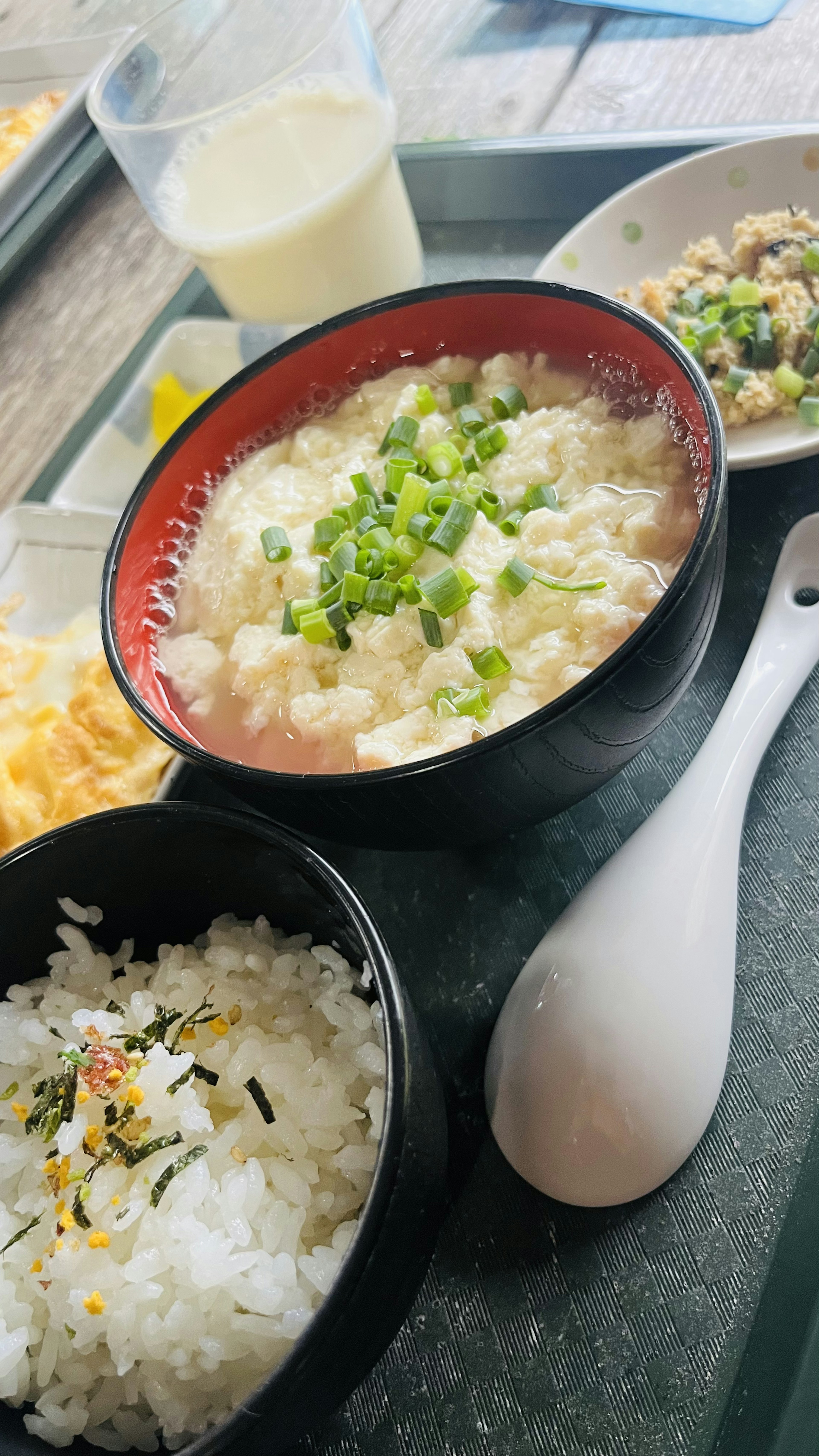 赤い器に盛られたネギ入りのご飯と白いご飯の皿があり、サイドに小皿と飲み物が見える