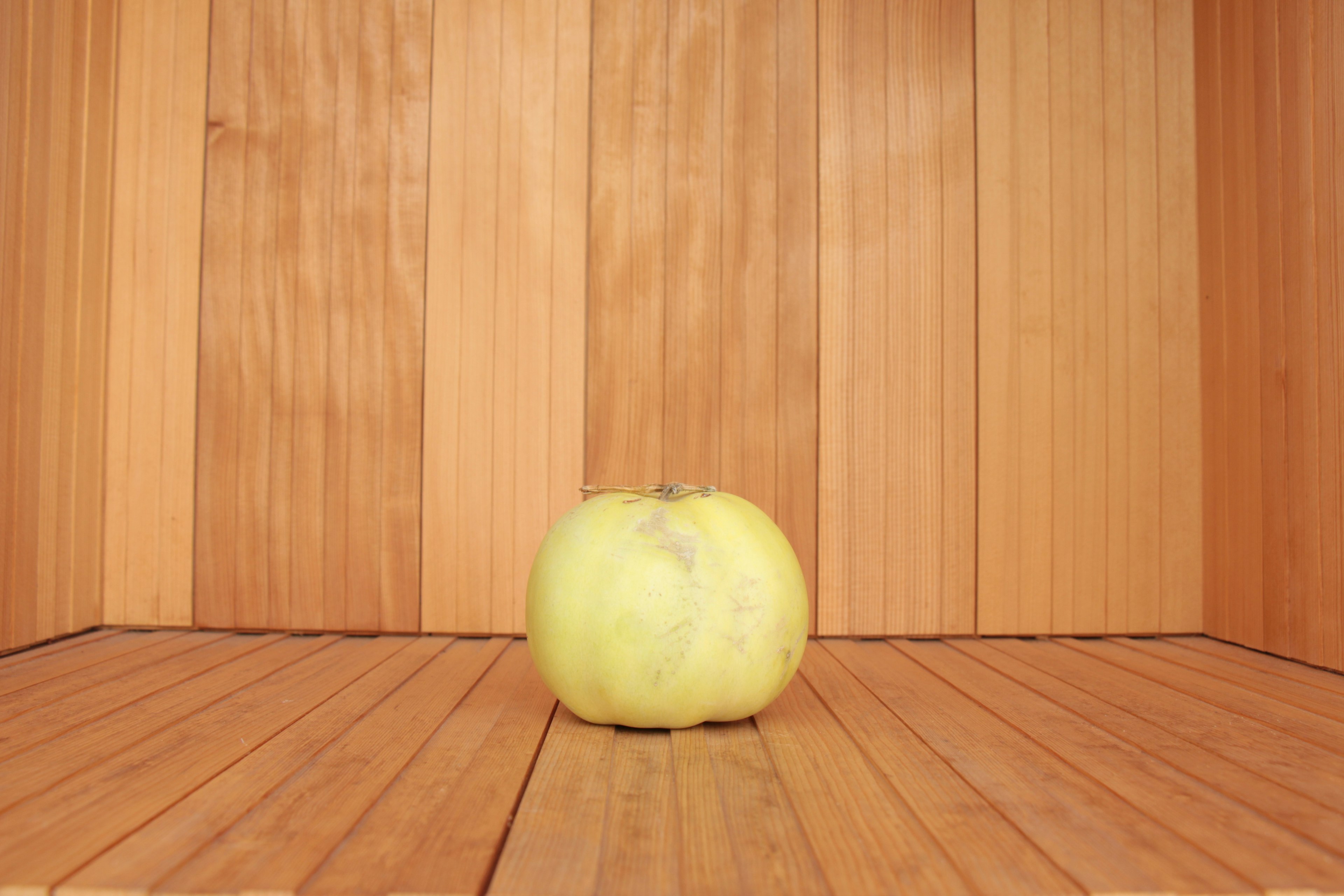 Pomme jaune placée devant des murs et un sol en bois