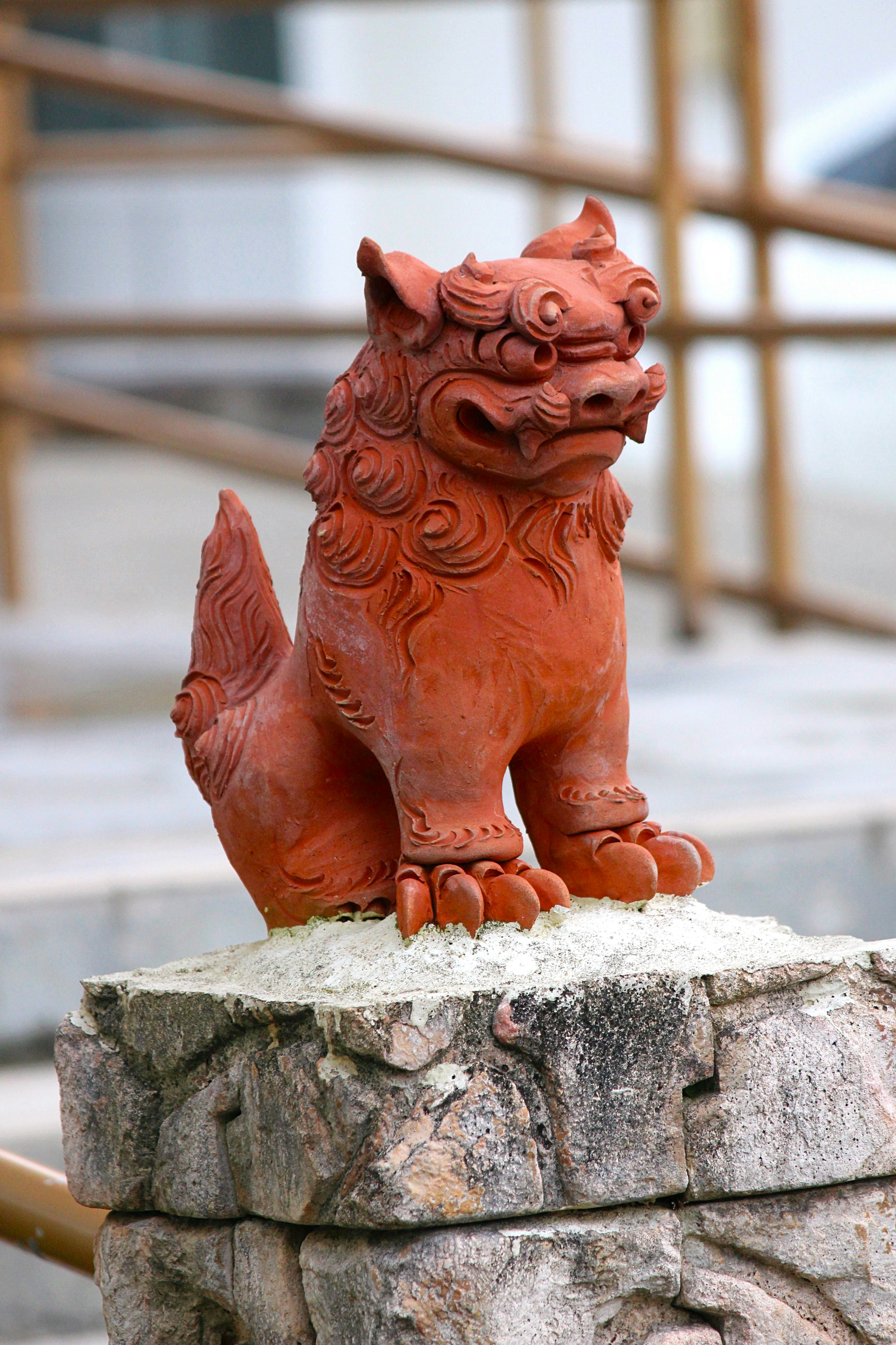 Statue de lion rouge assise sur une base en pierre