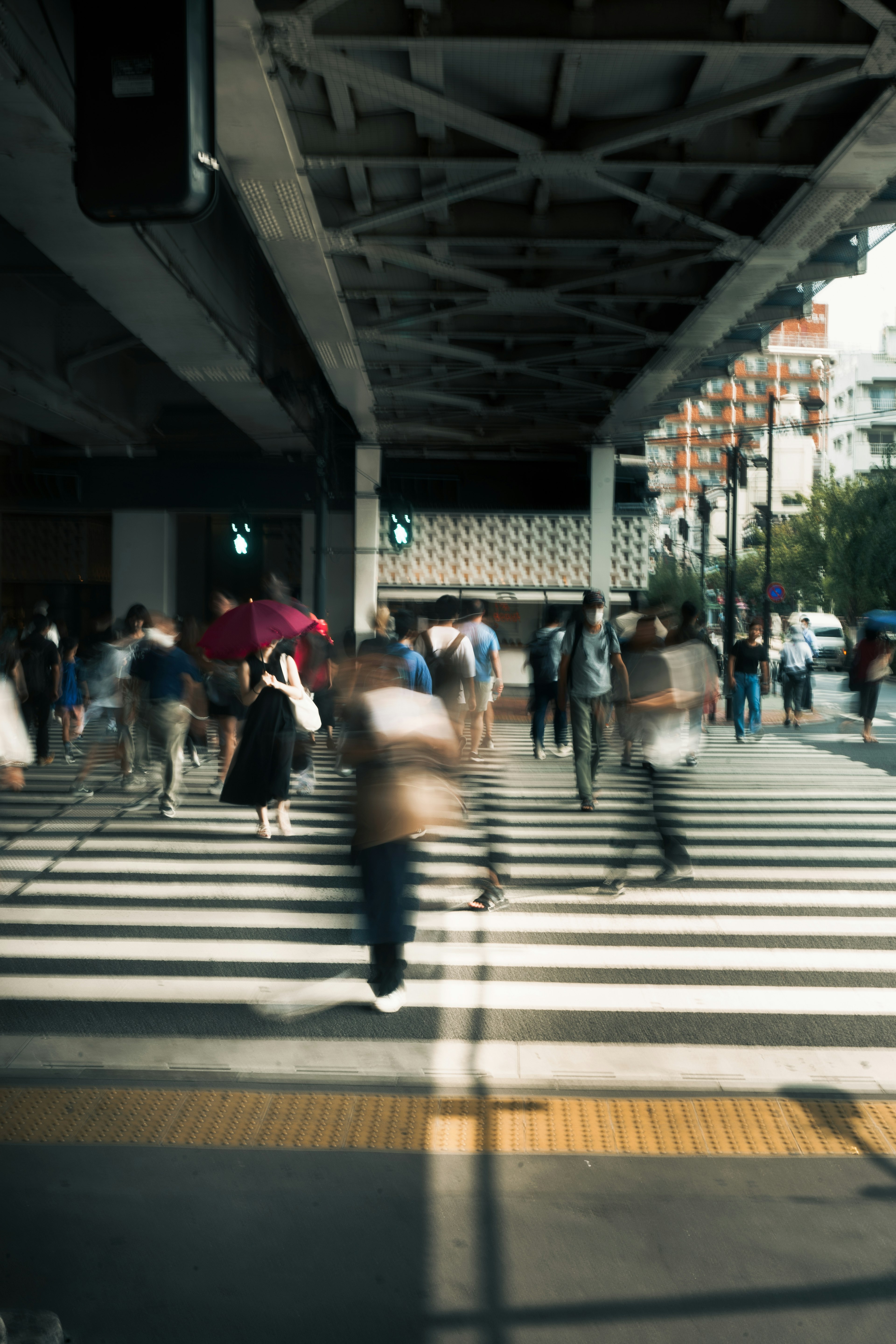 人们在斑马线上过马路，一位女性手持伞