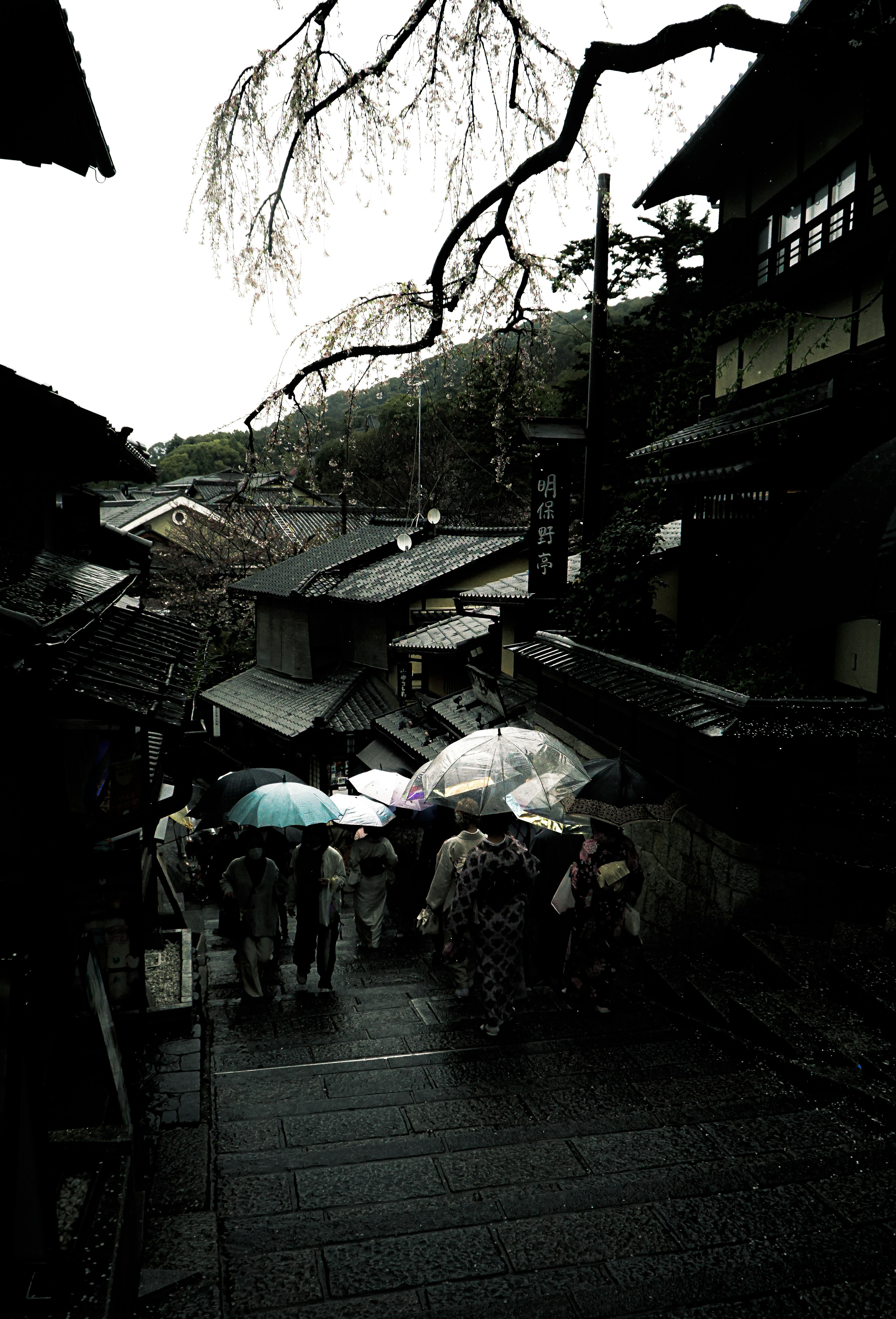 雨の中を歩く人々と傘がある古い街並みの風景