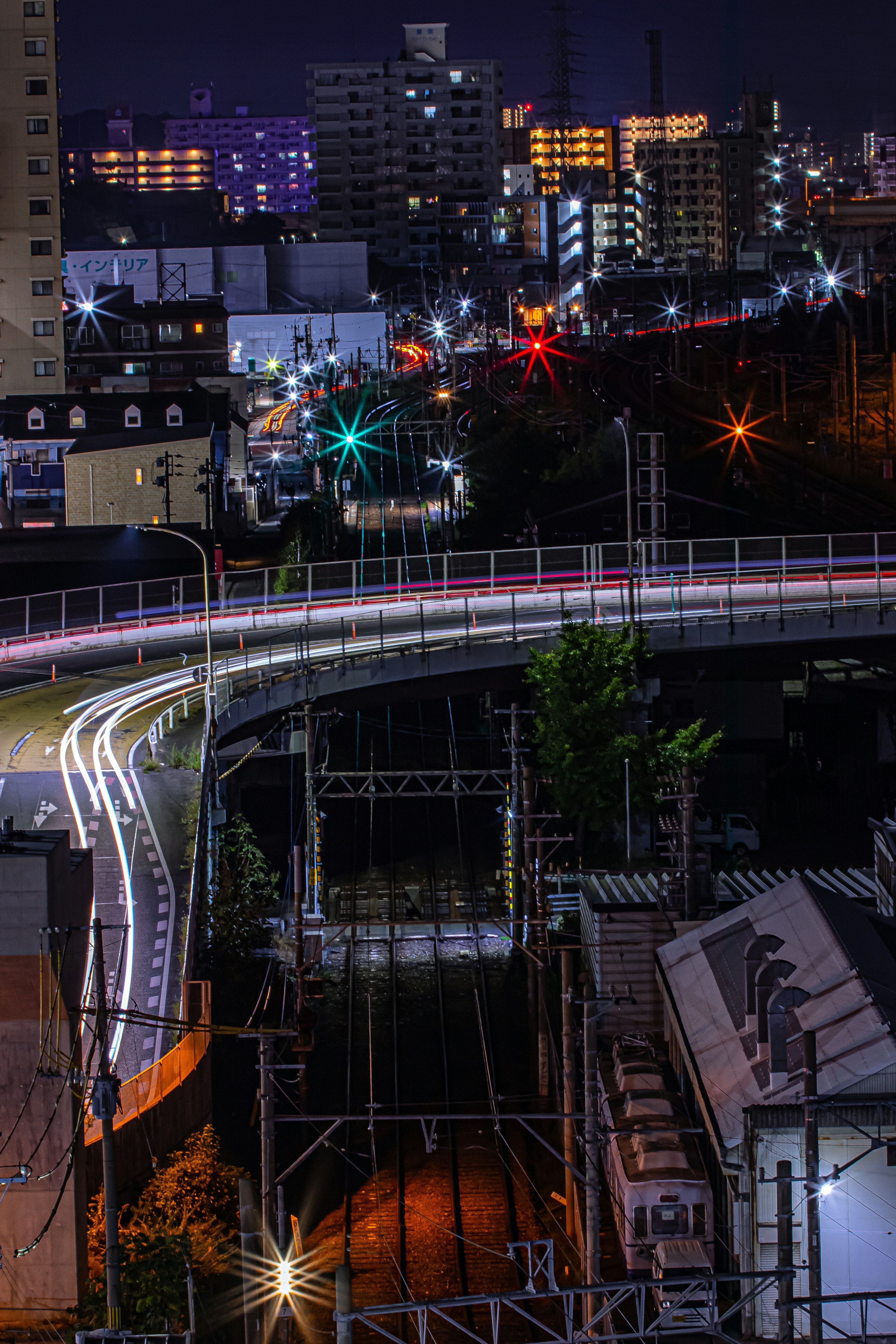 Paisaje urbano nocturno con luces de tren y edificios iluminados