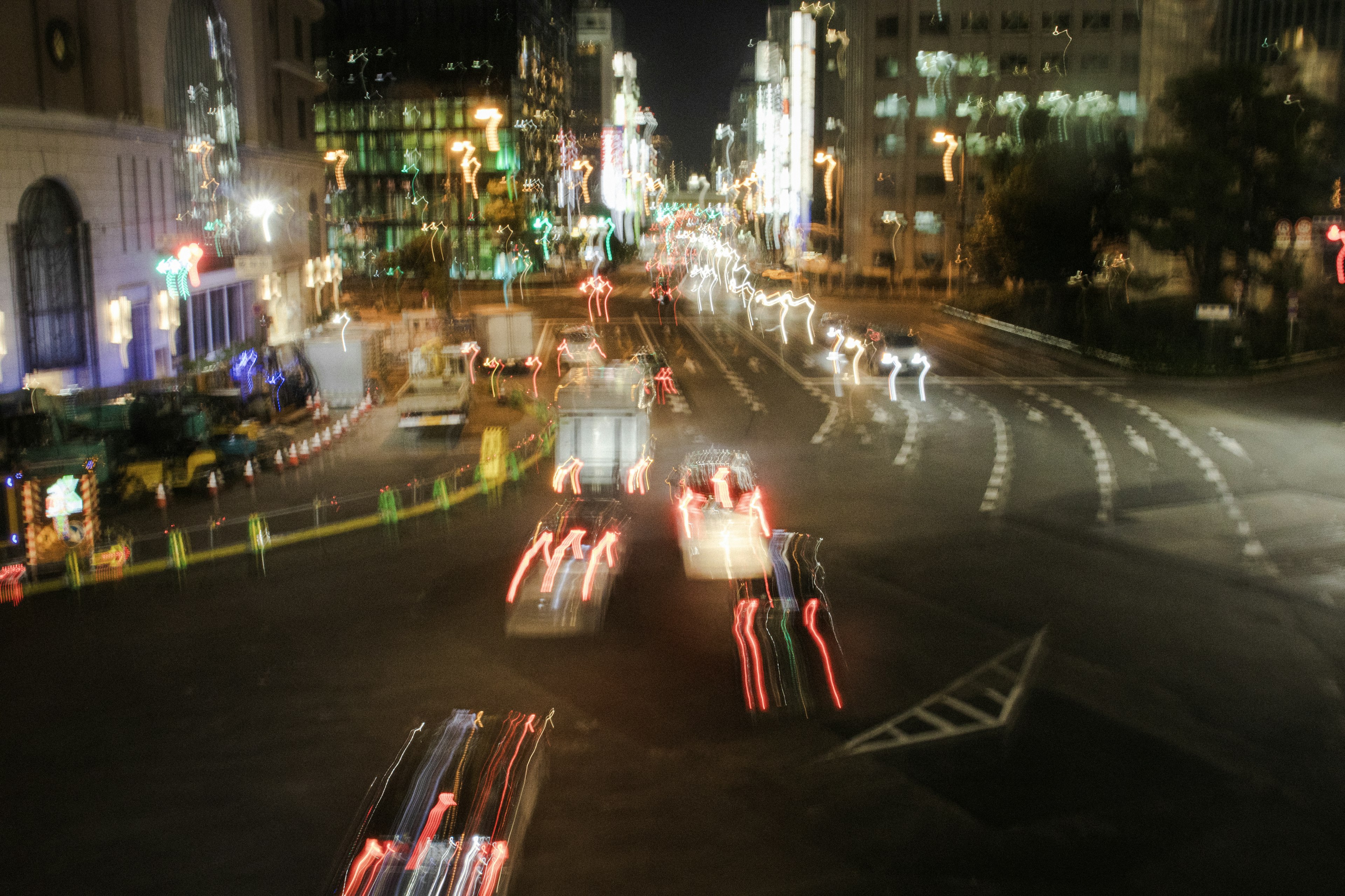 Light trails of cars at a city intersection at night with illuminated buildings