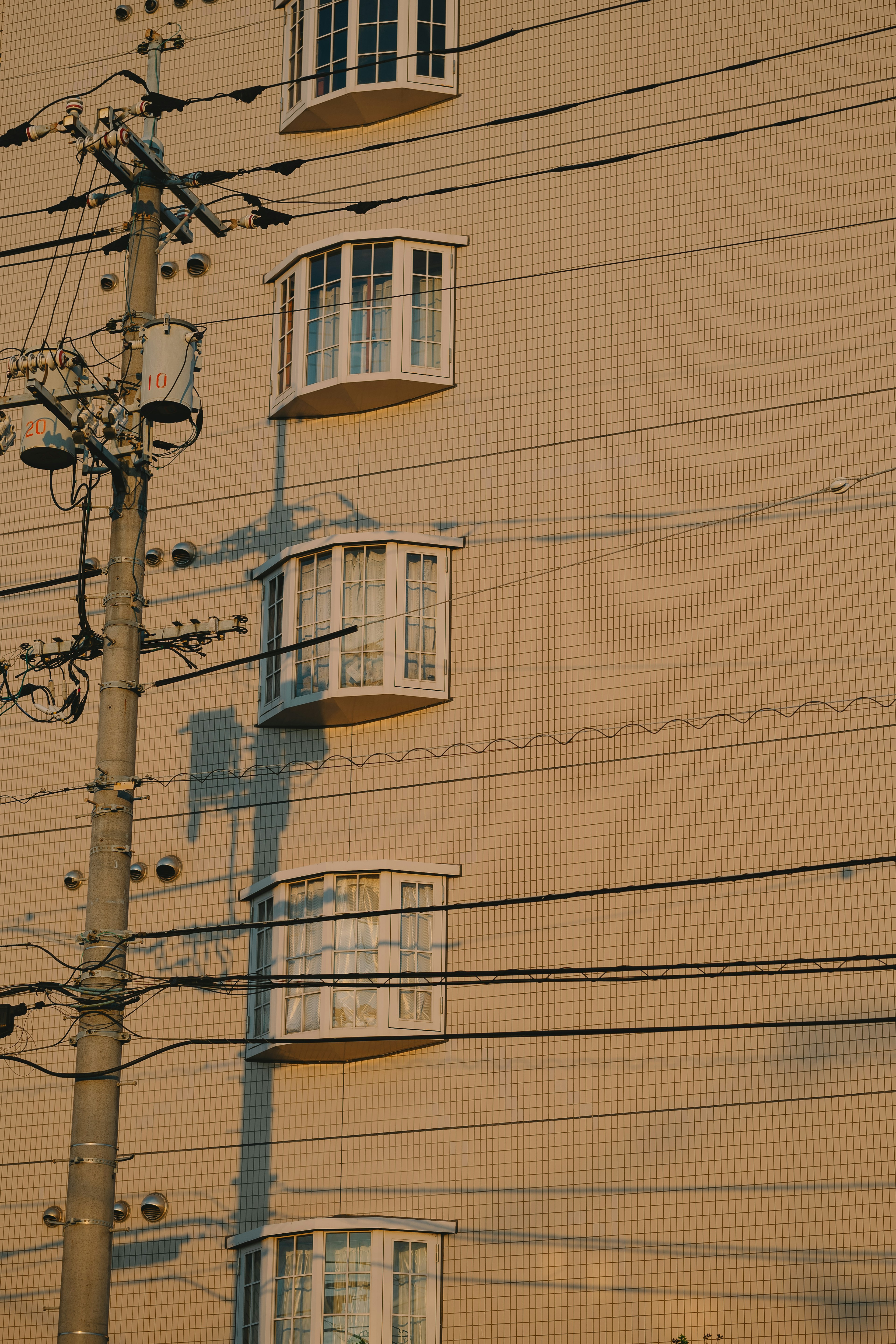 夕日が当たる建物の壁にある窓と電柱