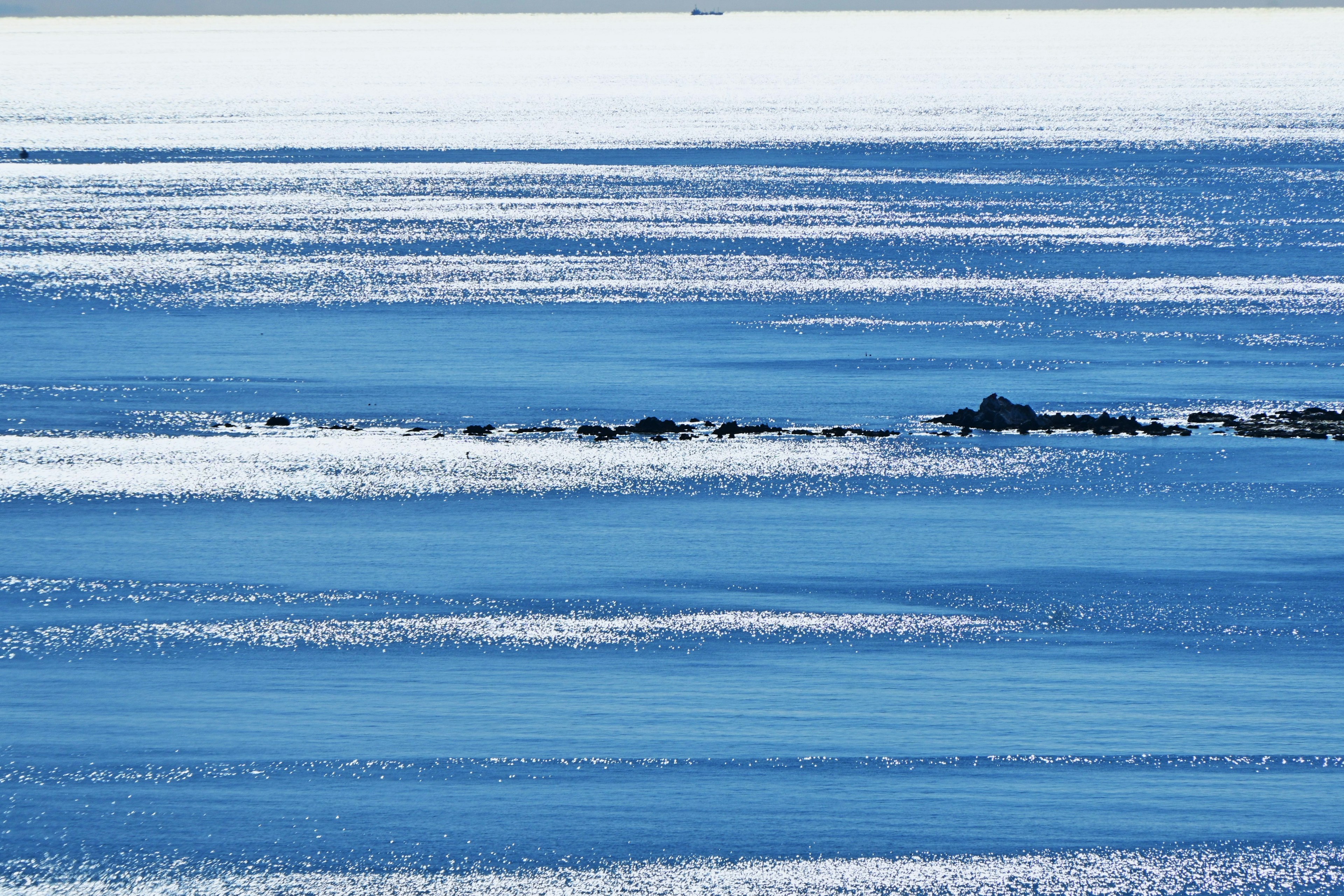 A scenic view of blue ocean with white wave stripes