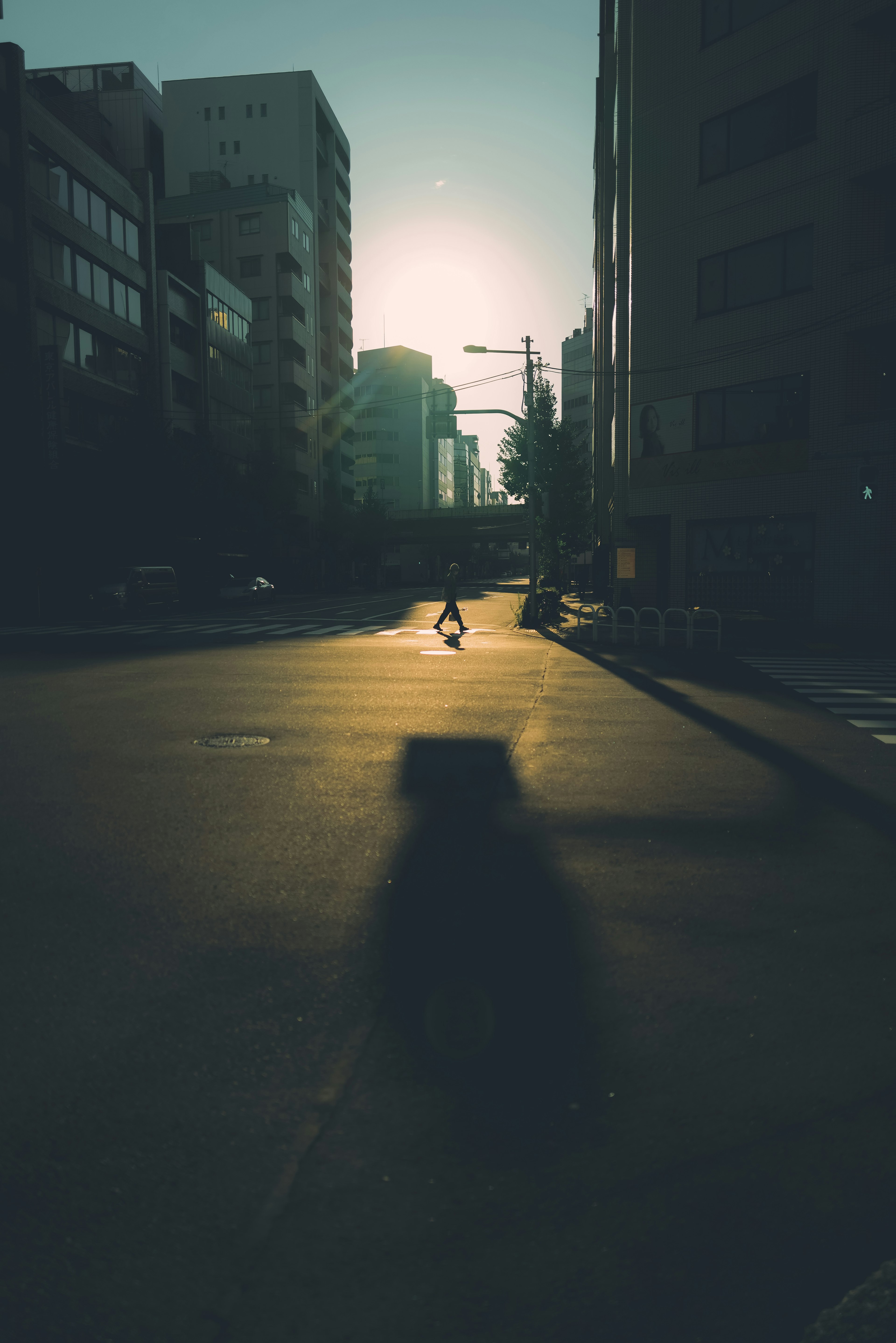 Silhouette d'une personne marchant sur une rue urbaine vide au coucher du soleil