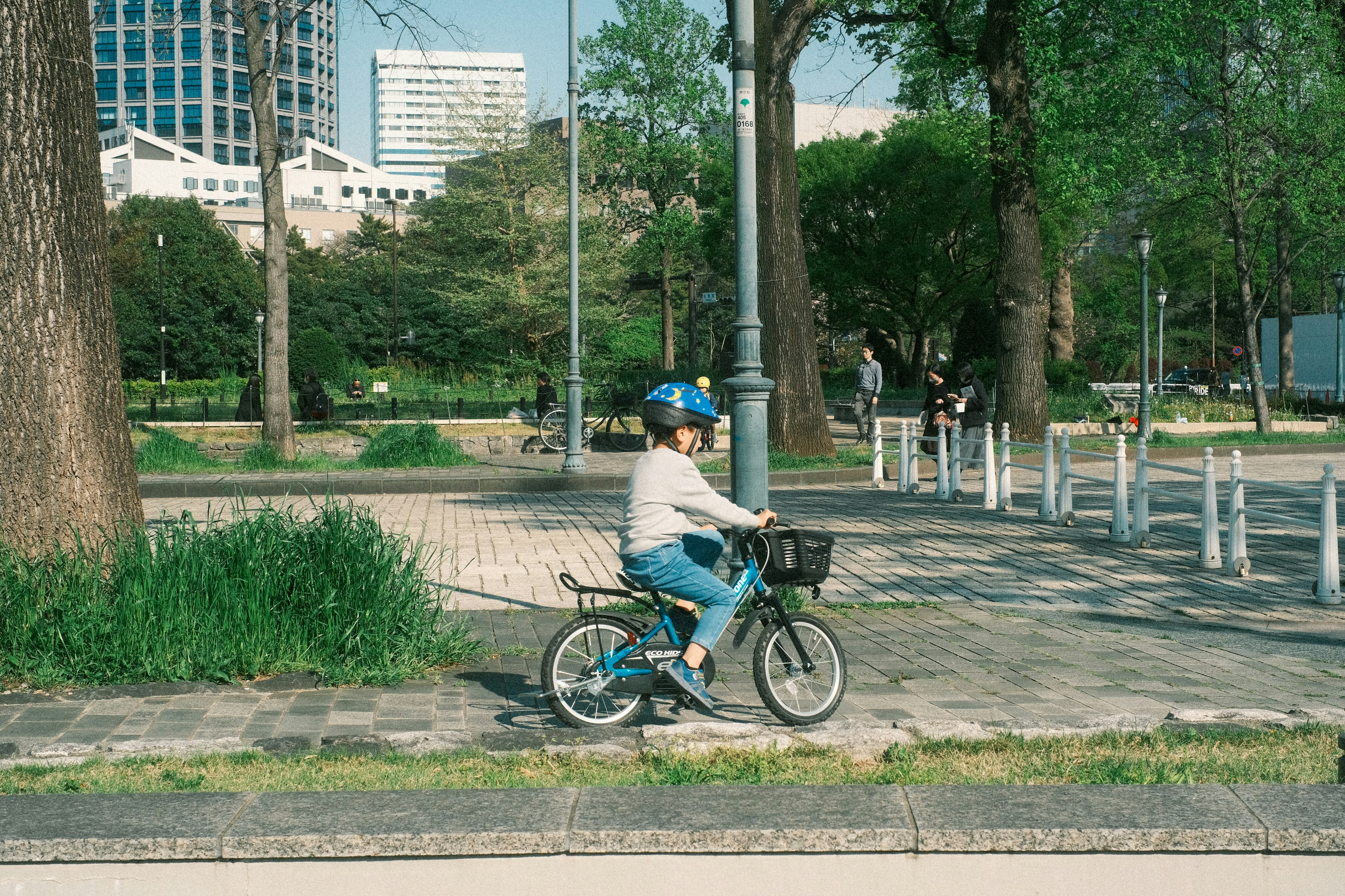 Niño montando una bicicleta en un parque usando un casco bicicleta azul rodeado de vegetación