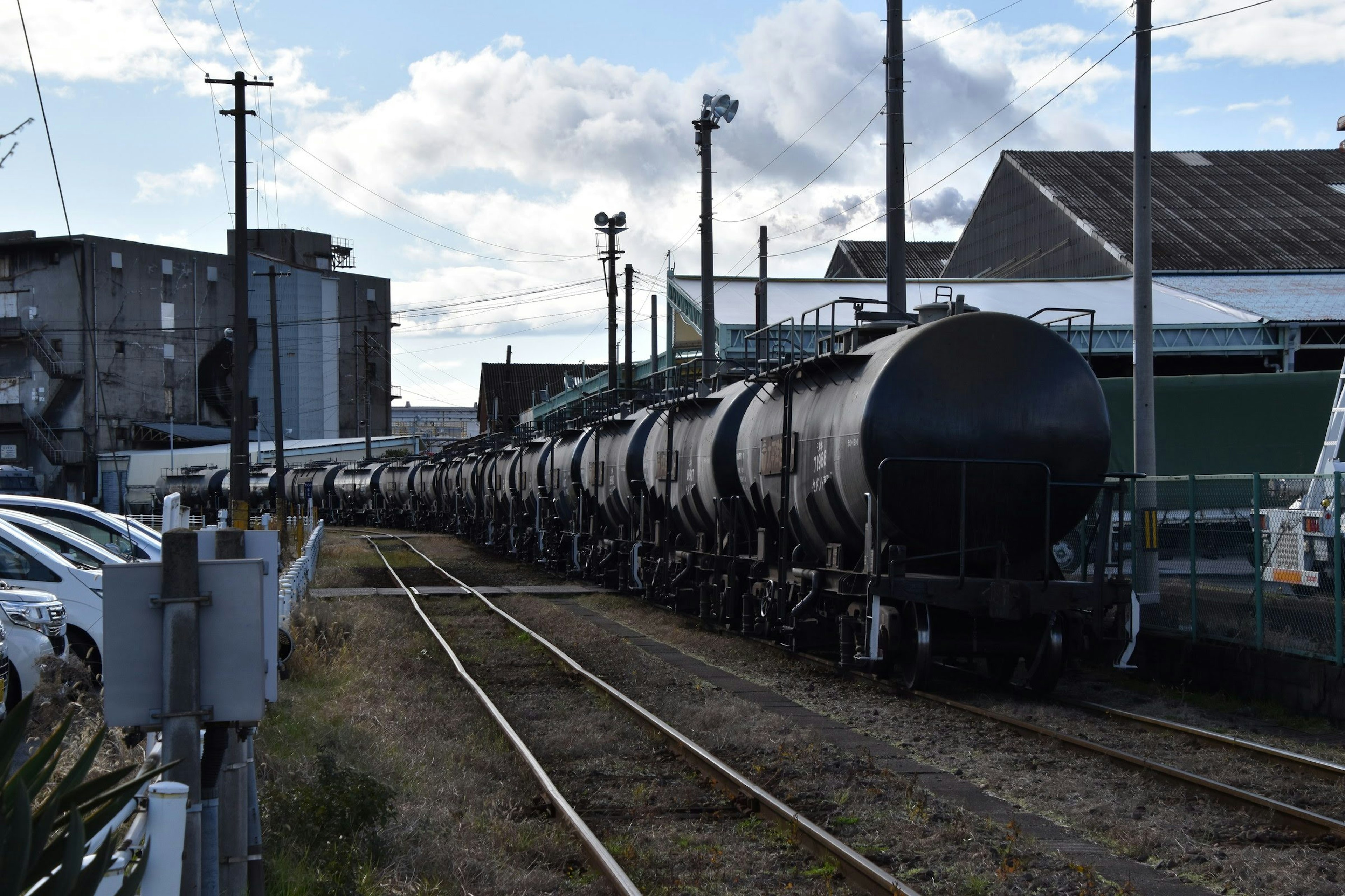 A scene of railway tank cars lined up with factories and buildings in the background