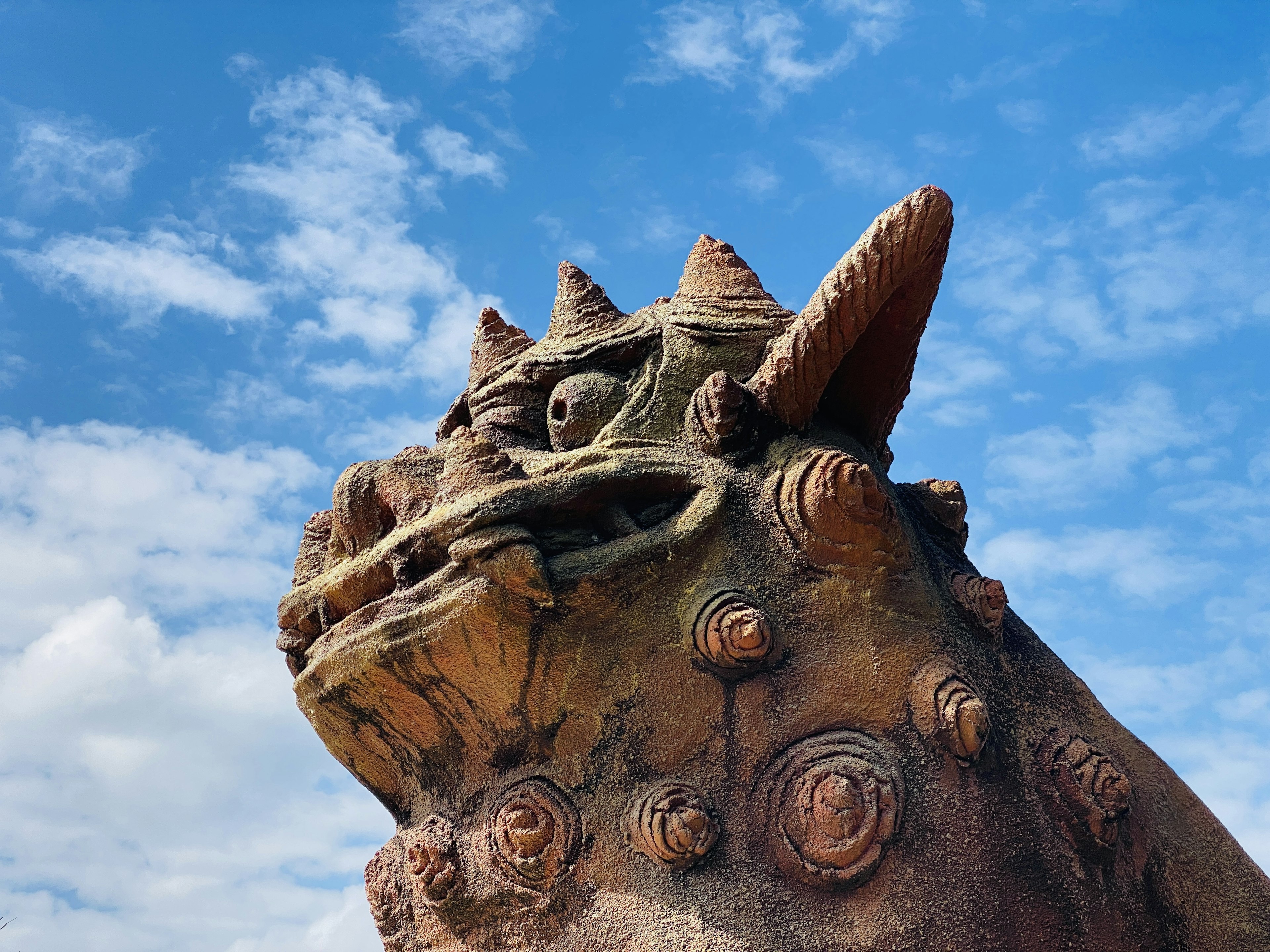 Side view of a dragon sculpture under a blue sky