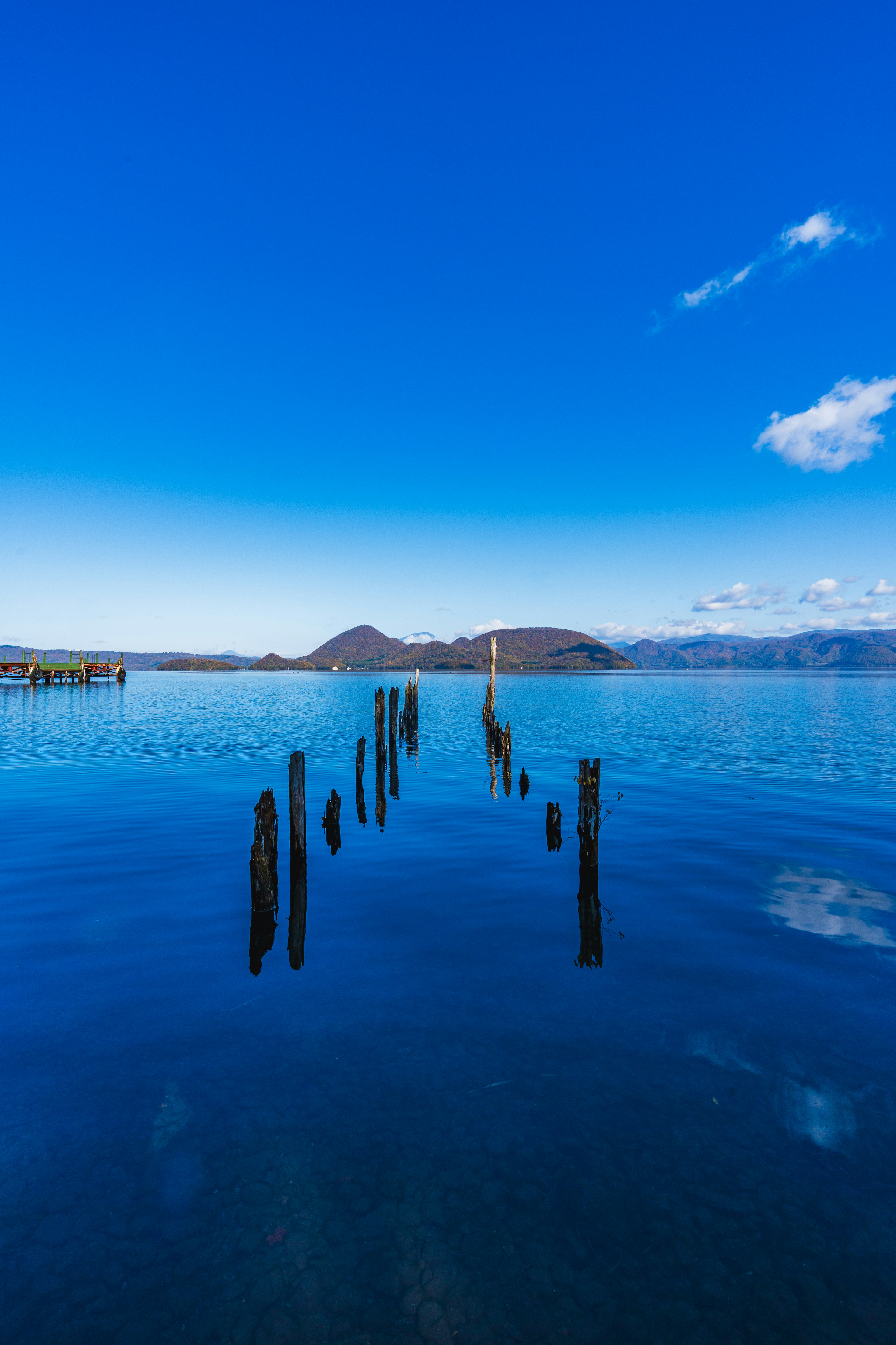 Vista panoramica di un cielo blu chiaro e acqua calma con pali di legno che si estendono nel lago