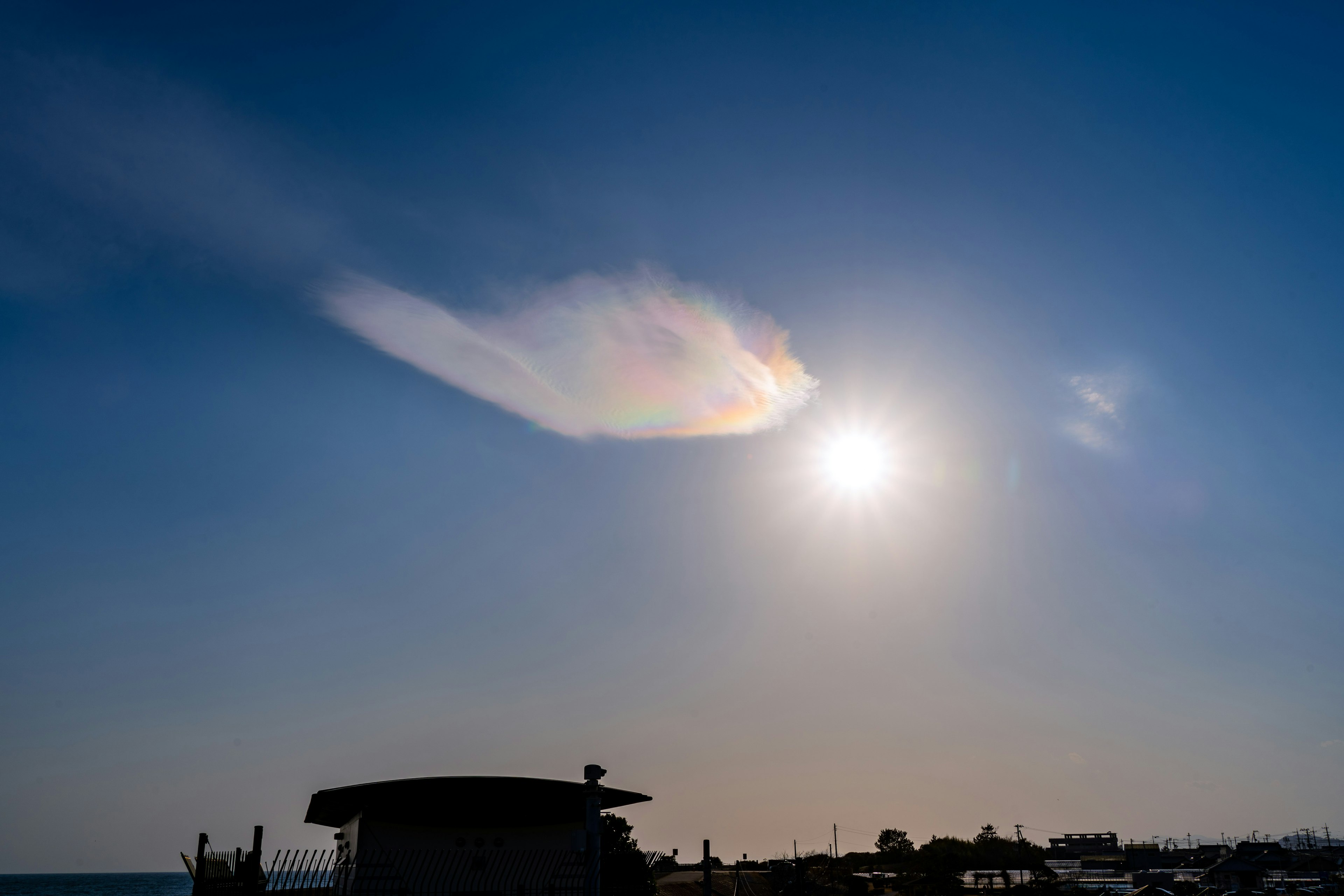 Rainbow-colored cloud in a blue sky with bright sunlight