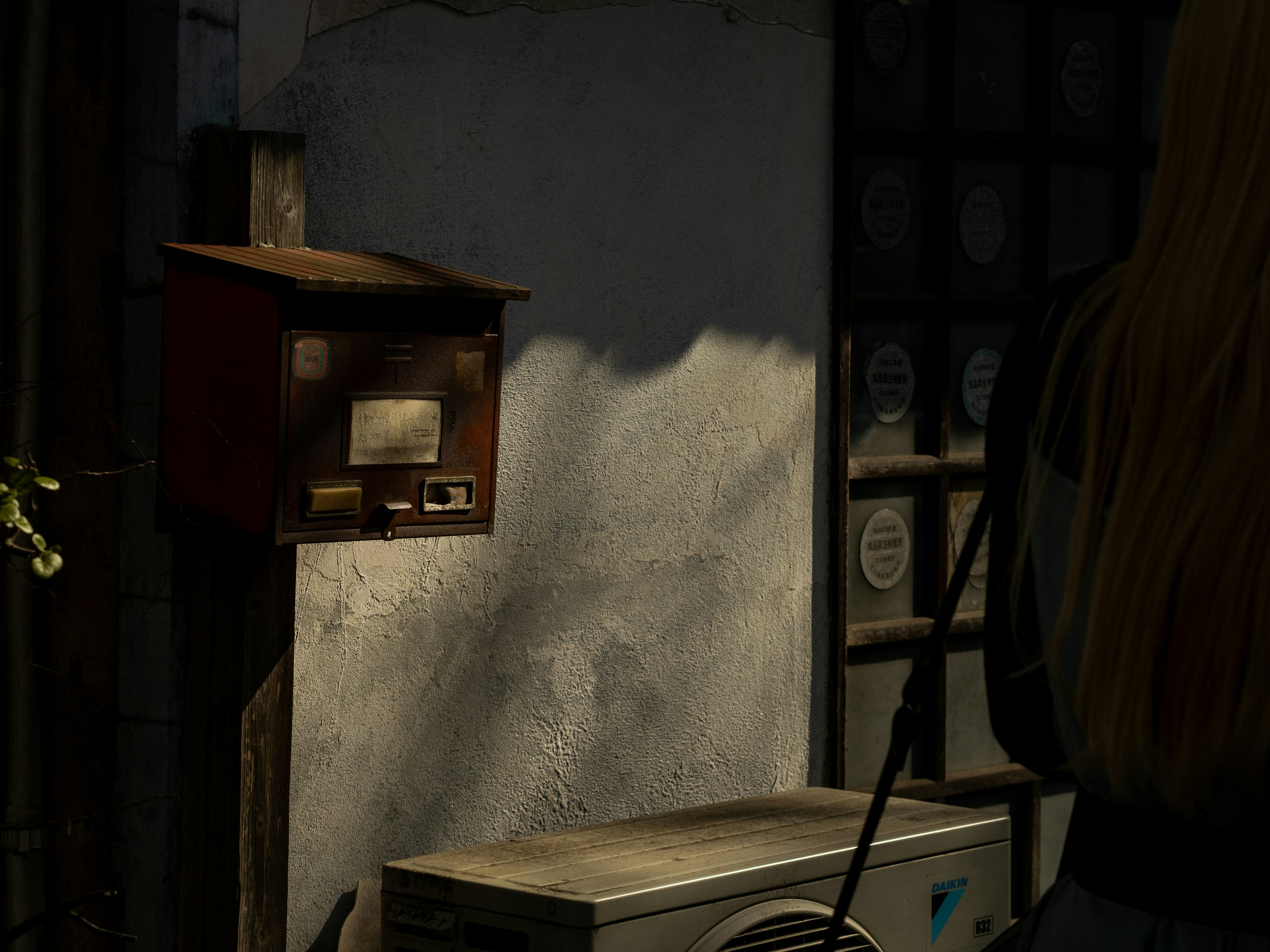 Red mailbox against a textured wall with an air conditioning unit