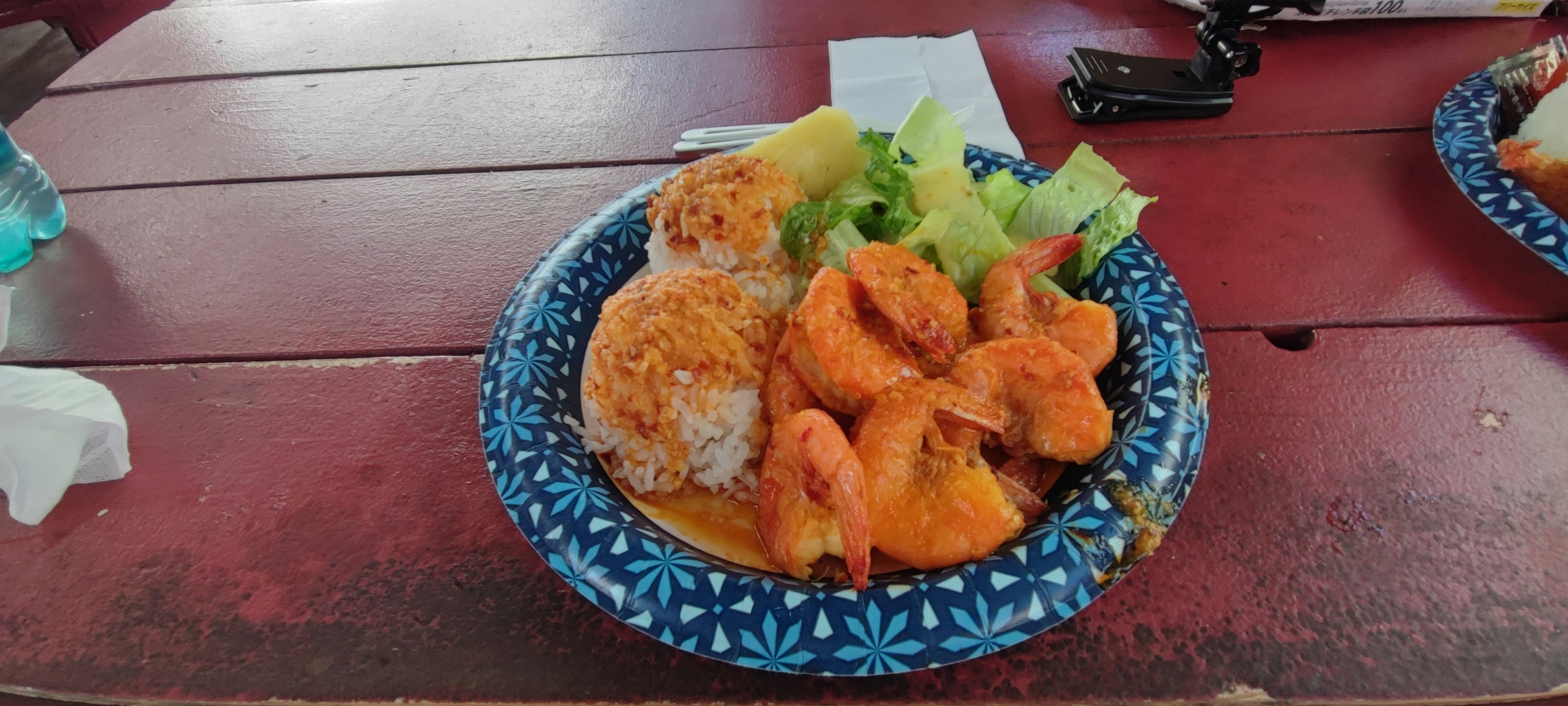 A plate of colorful food including fried shrimp and rice balls