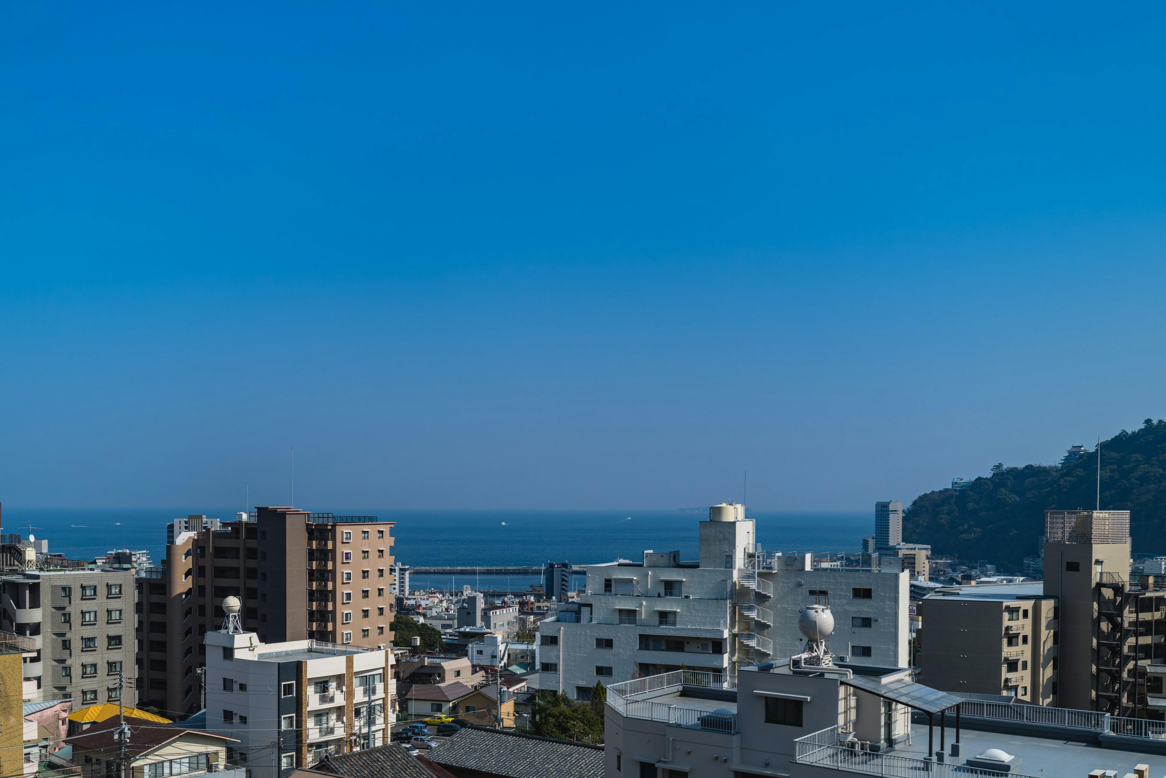 Paisaje urbano con edificios altos bajo un cielo azul claro y el océano al fondo