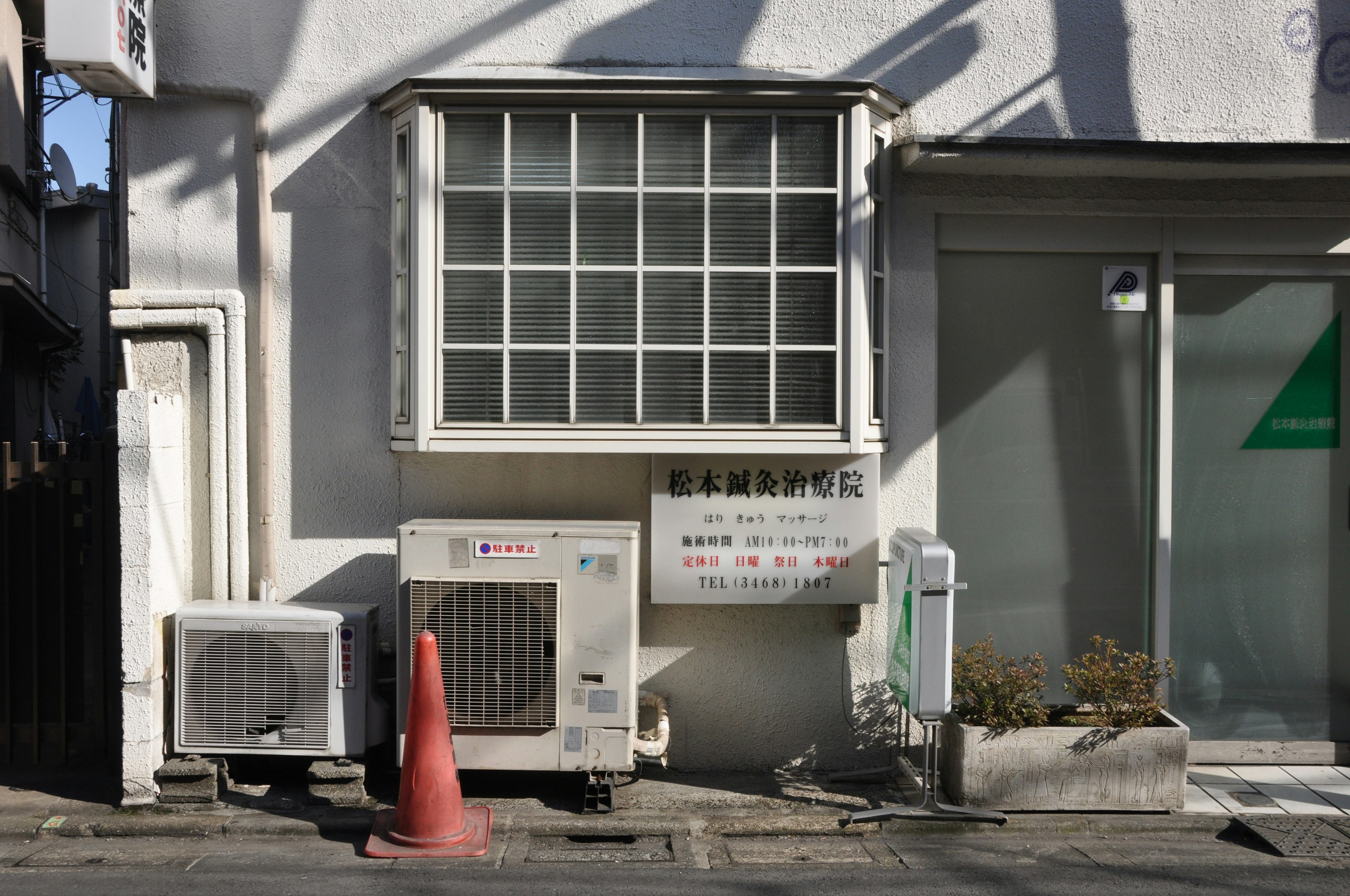 白色建築牆邊的空調和橙色錐