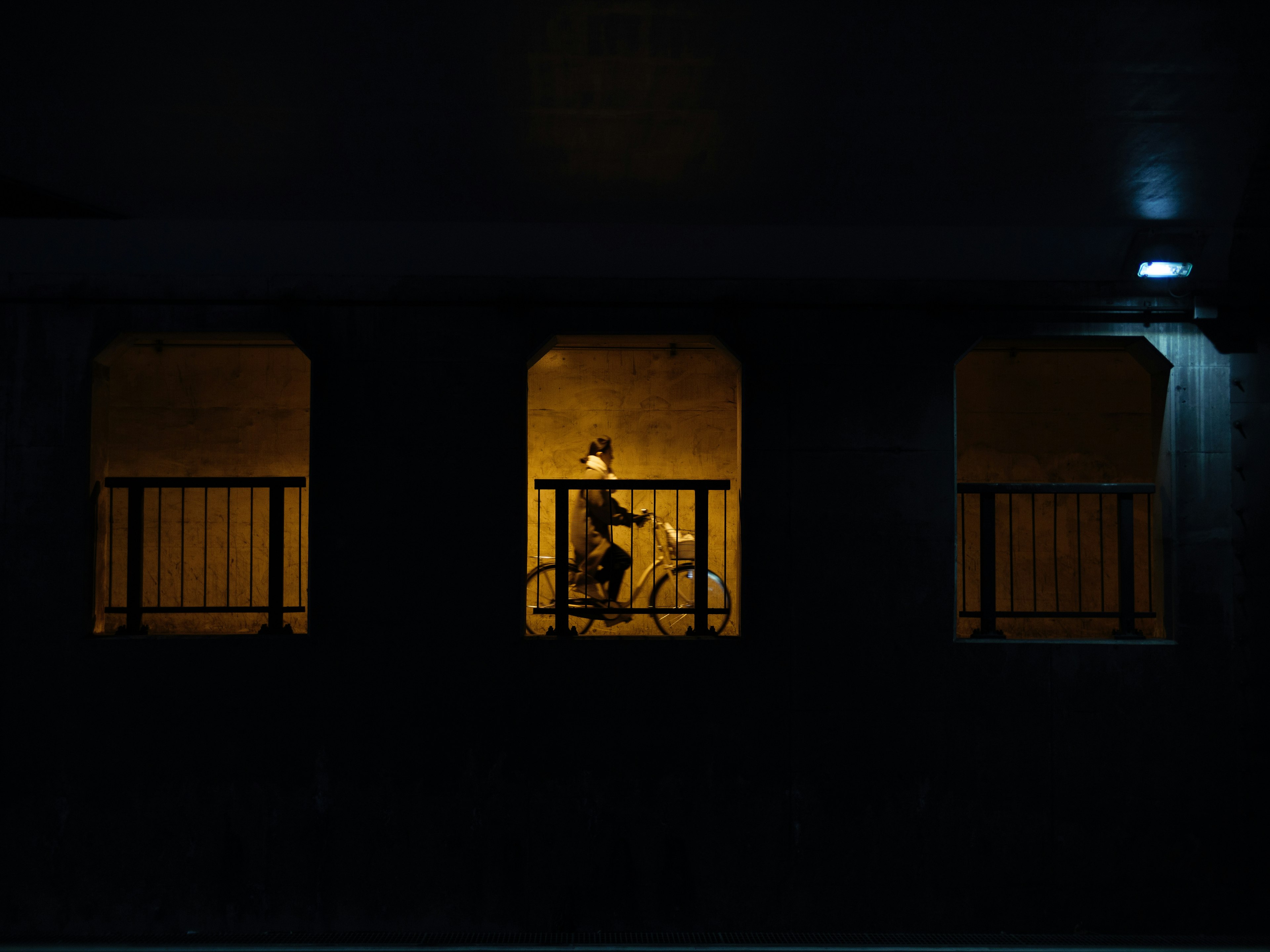 A person riding a bicycle illuminated by yellow light in a dark tunnel