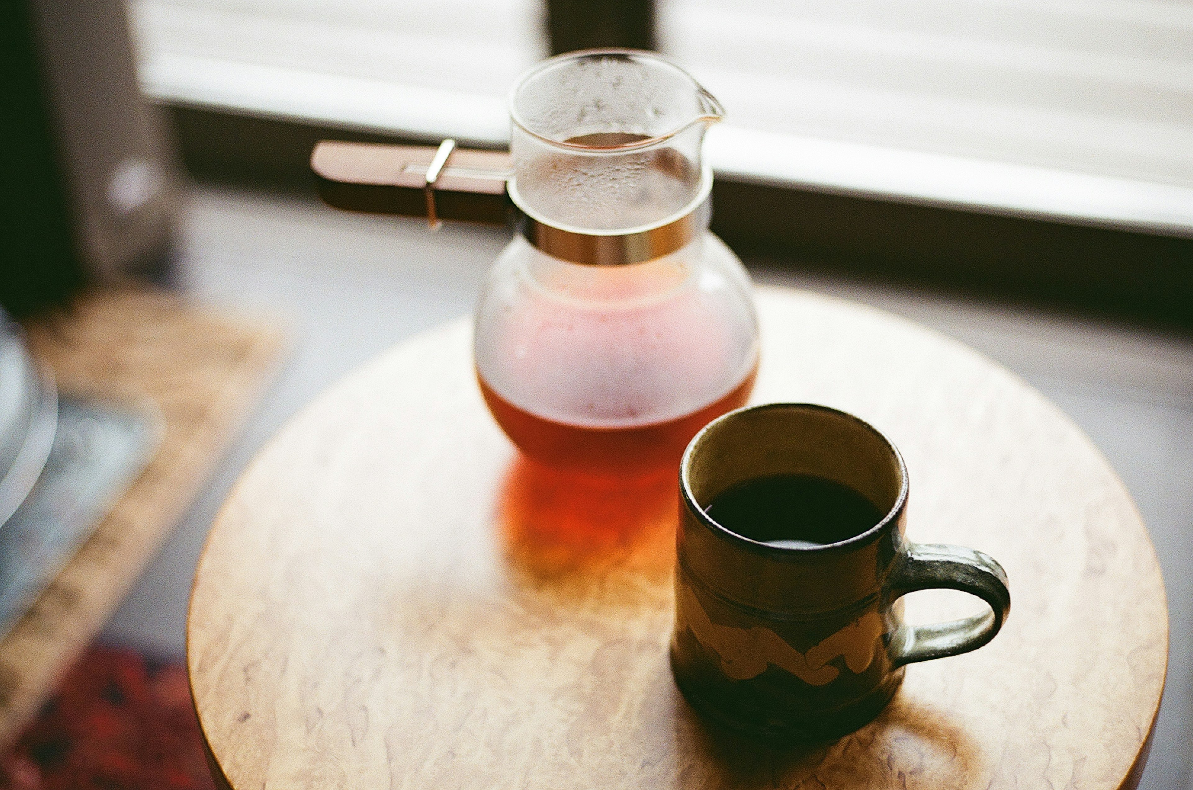 Imagen de una cafetera y una taza colocadas sobre una mesa