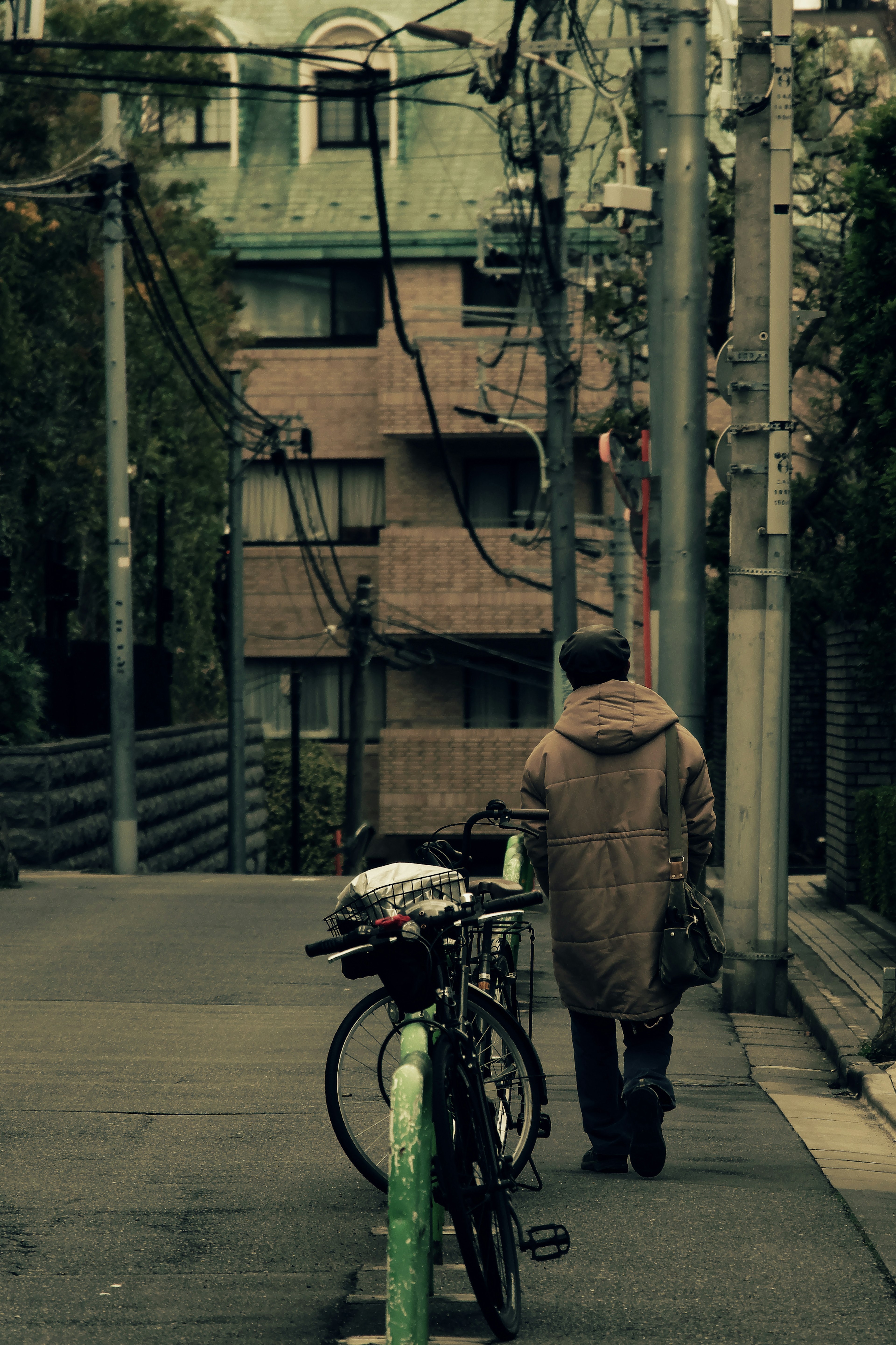 A person walking down a street with a bicycle parked nearby