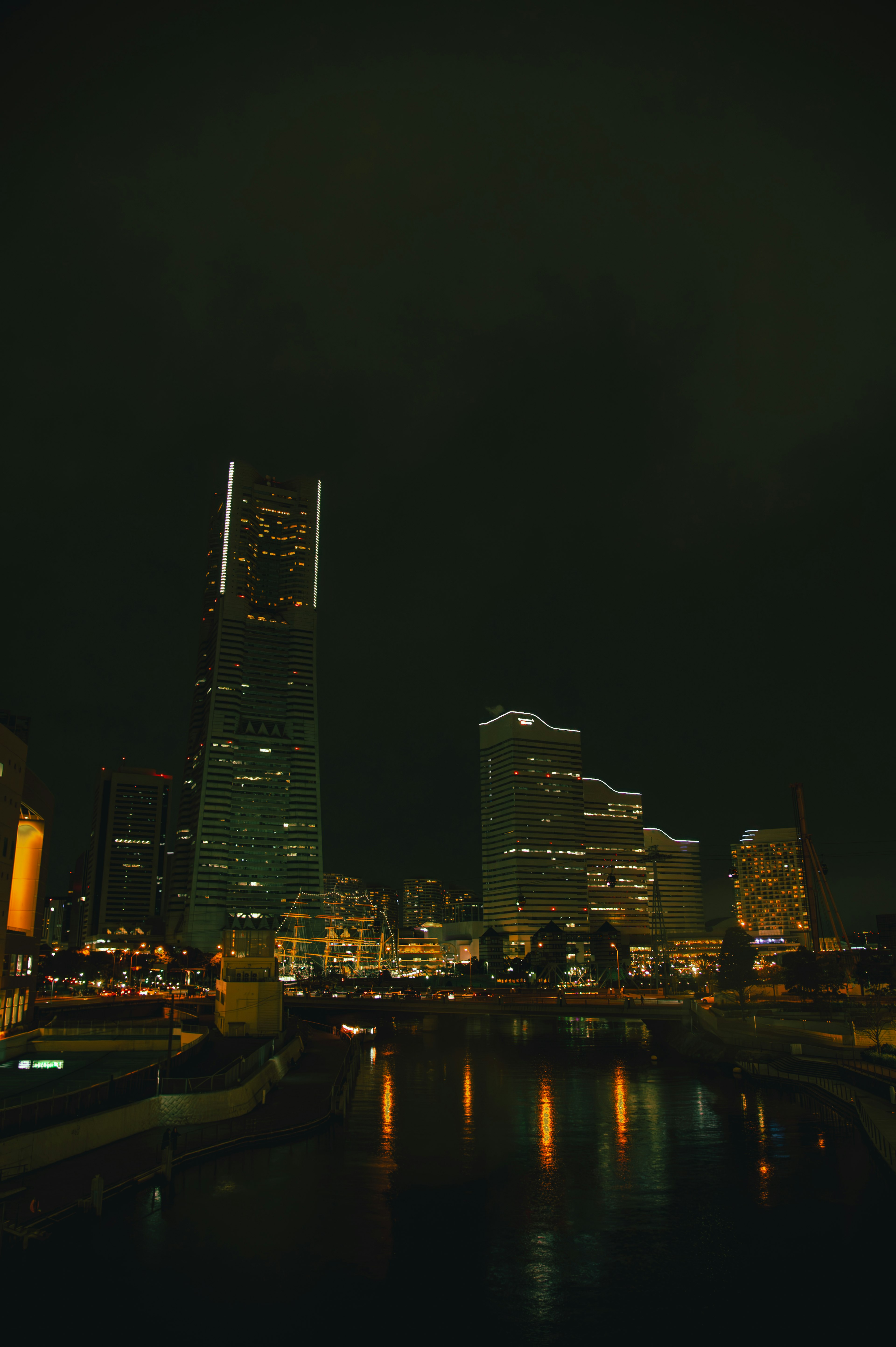 Skyline of skyscrapers illuminated at night with a river in the foreground