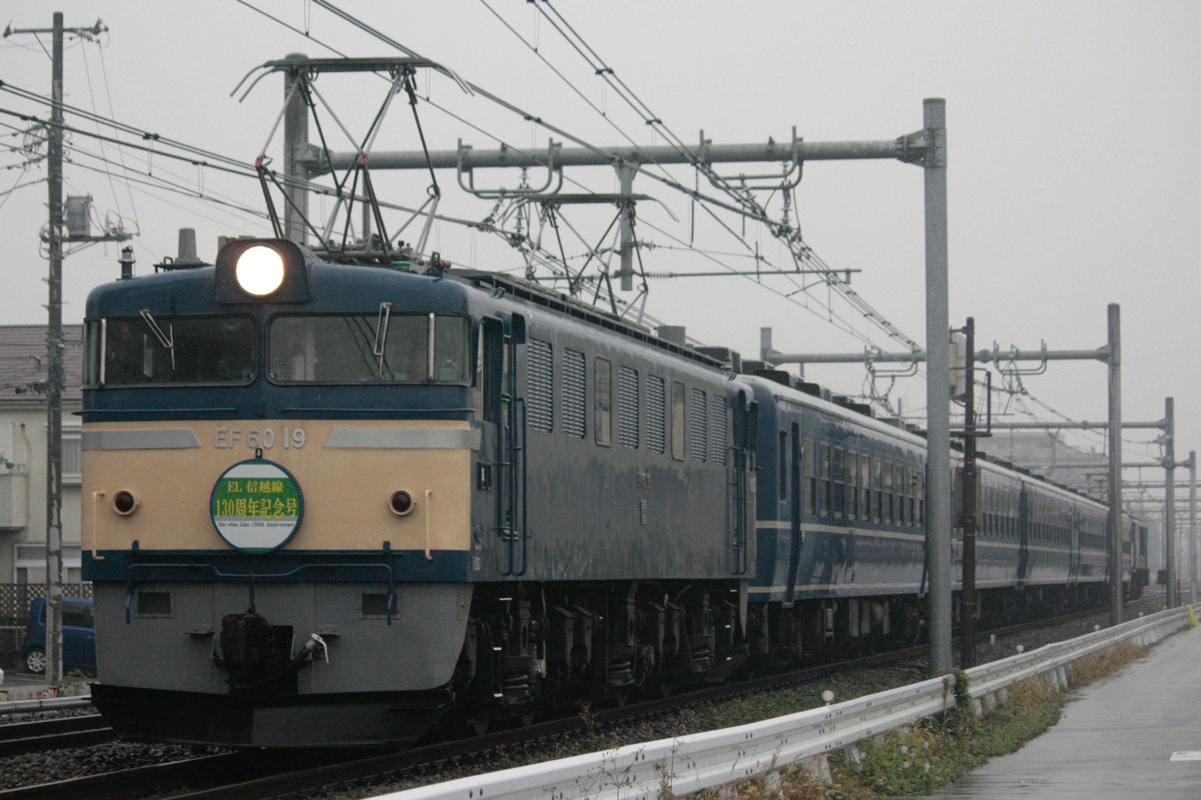 青い電車が雨の中を走っている風景