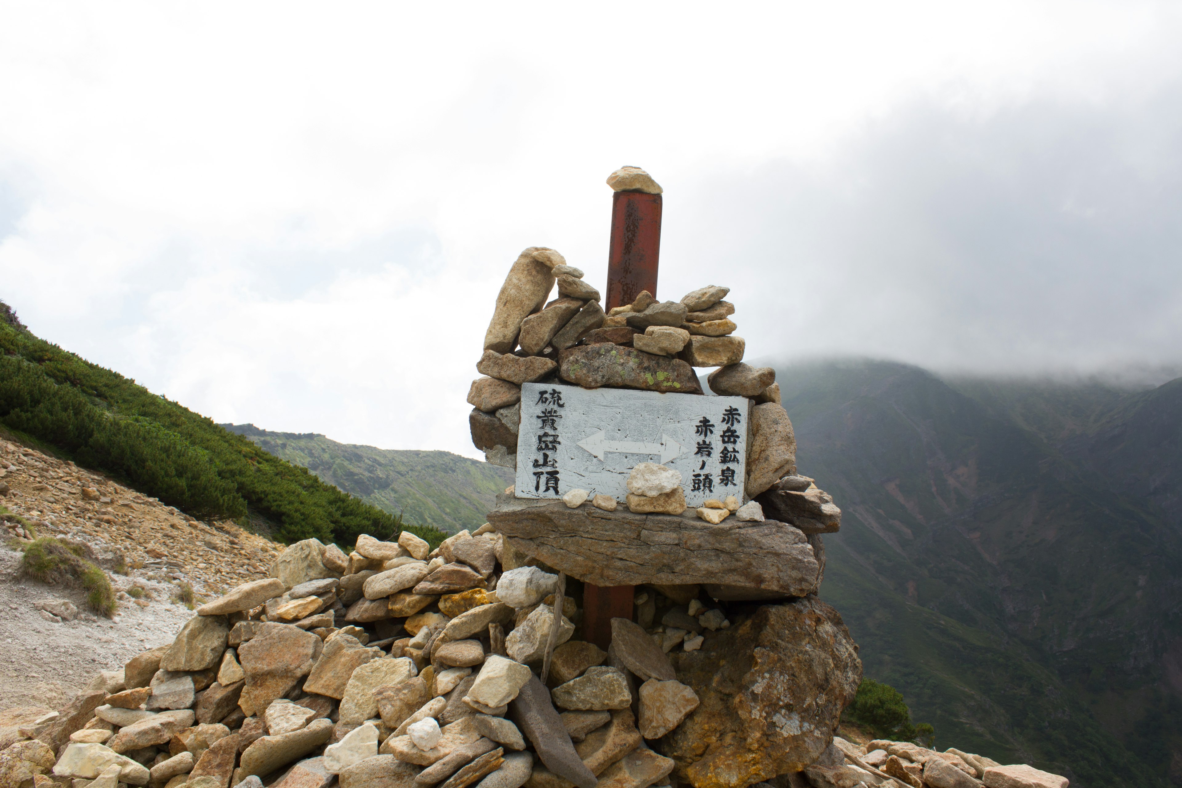 산 정상에 있는 돌 더미와 표지판