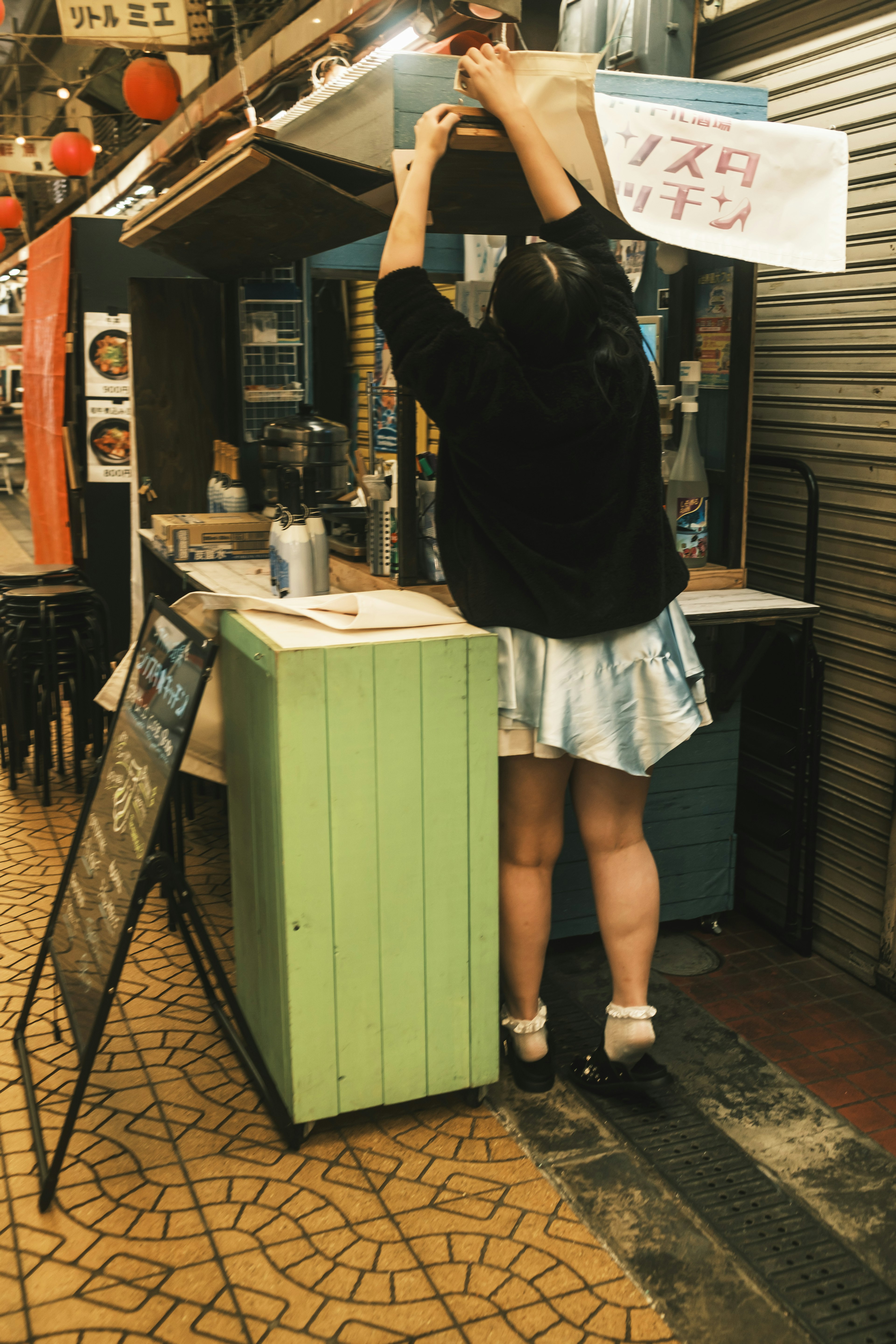 A woman adjusting a sign at a street food stall