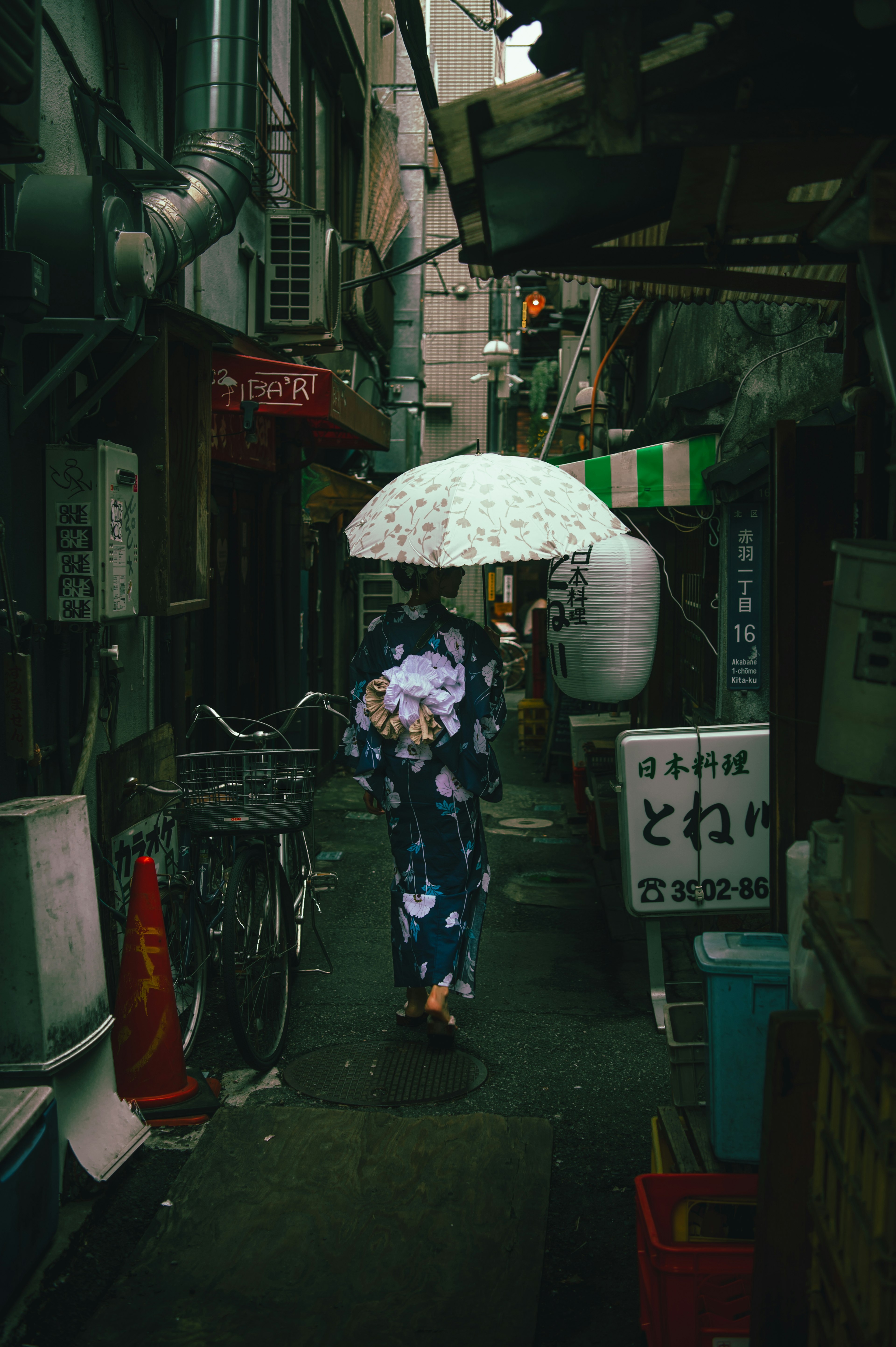 Wanita berpakaian kimono berjalan di gang sempit dengan payung