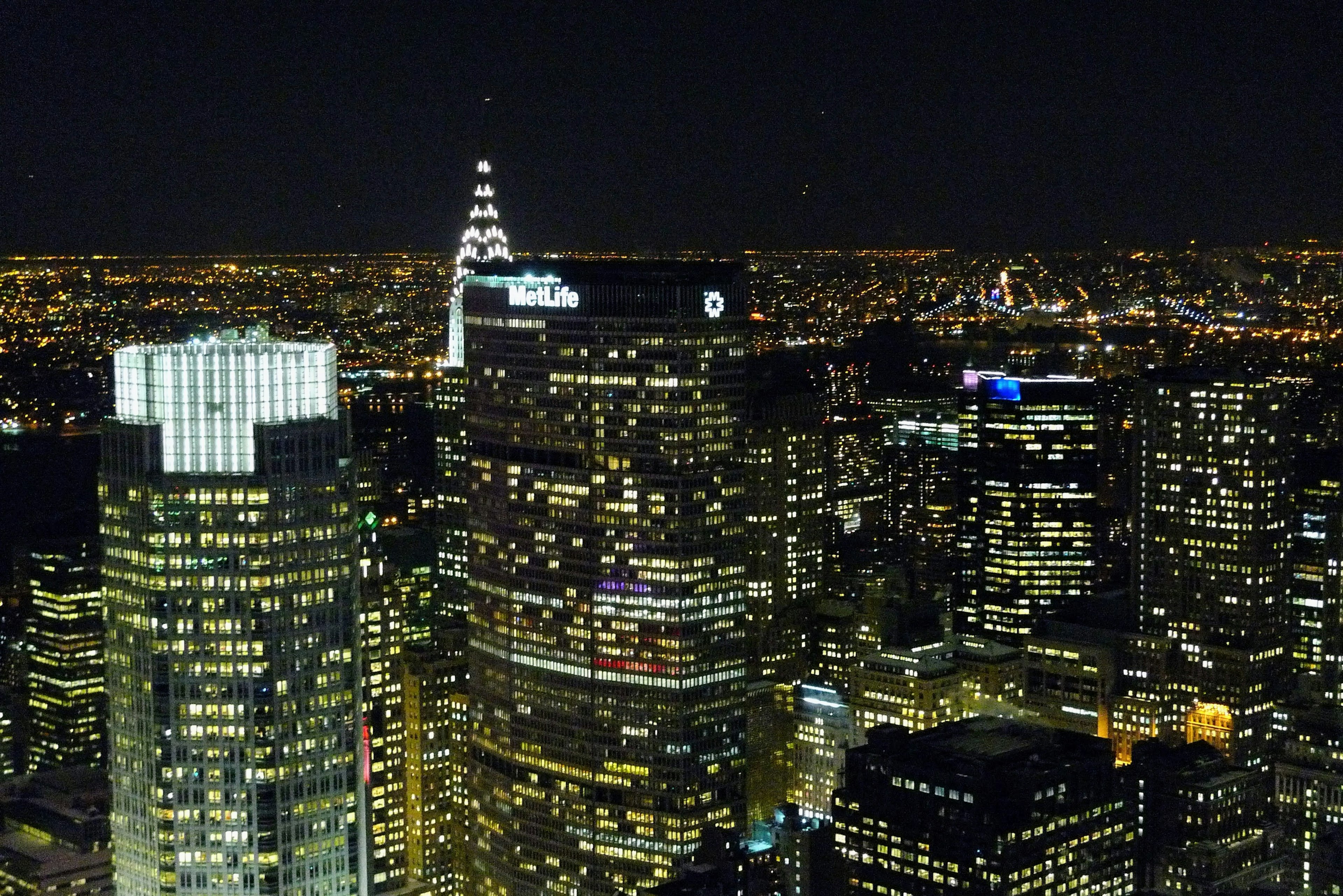 Night city skyline featuring skyscrapers and bright lights including the iconic spire of the Empire State Building