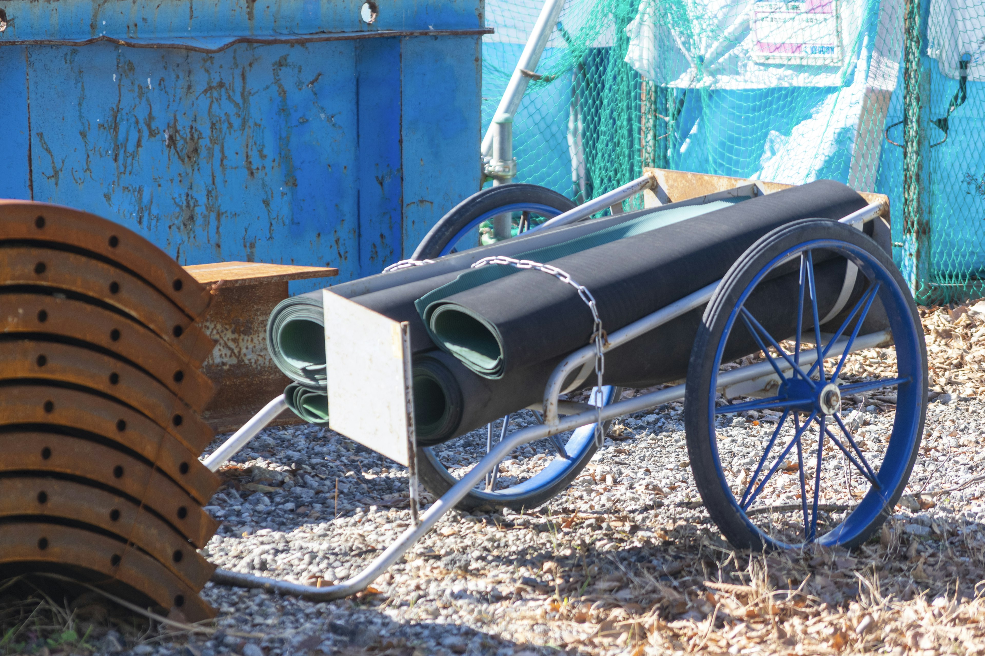 Un carrito con alfombrillas negras enrolladas colocado contra un fondo azul