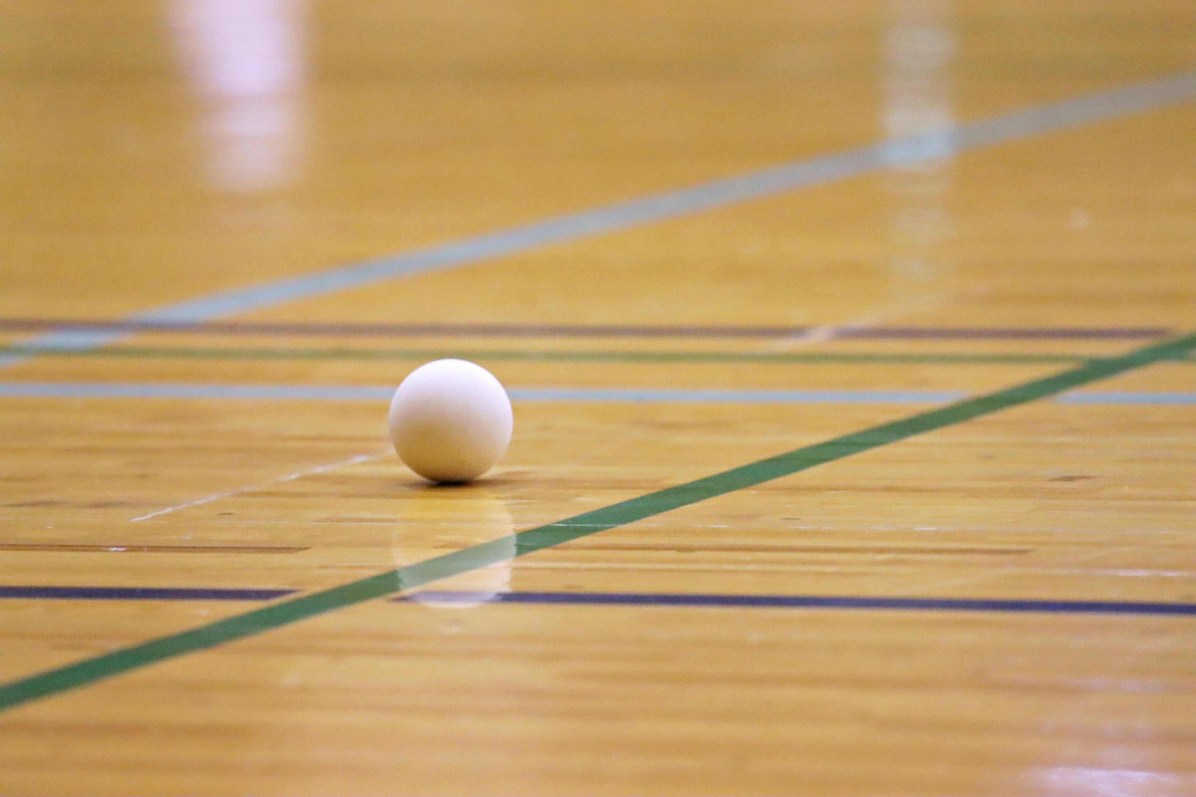 Une balle blanche sur un sol de gymnase en bois