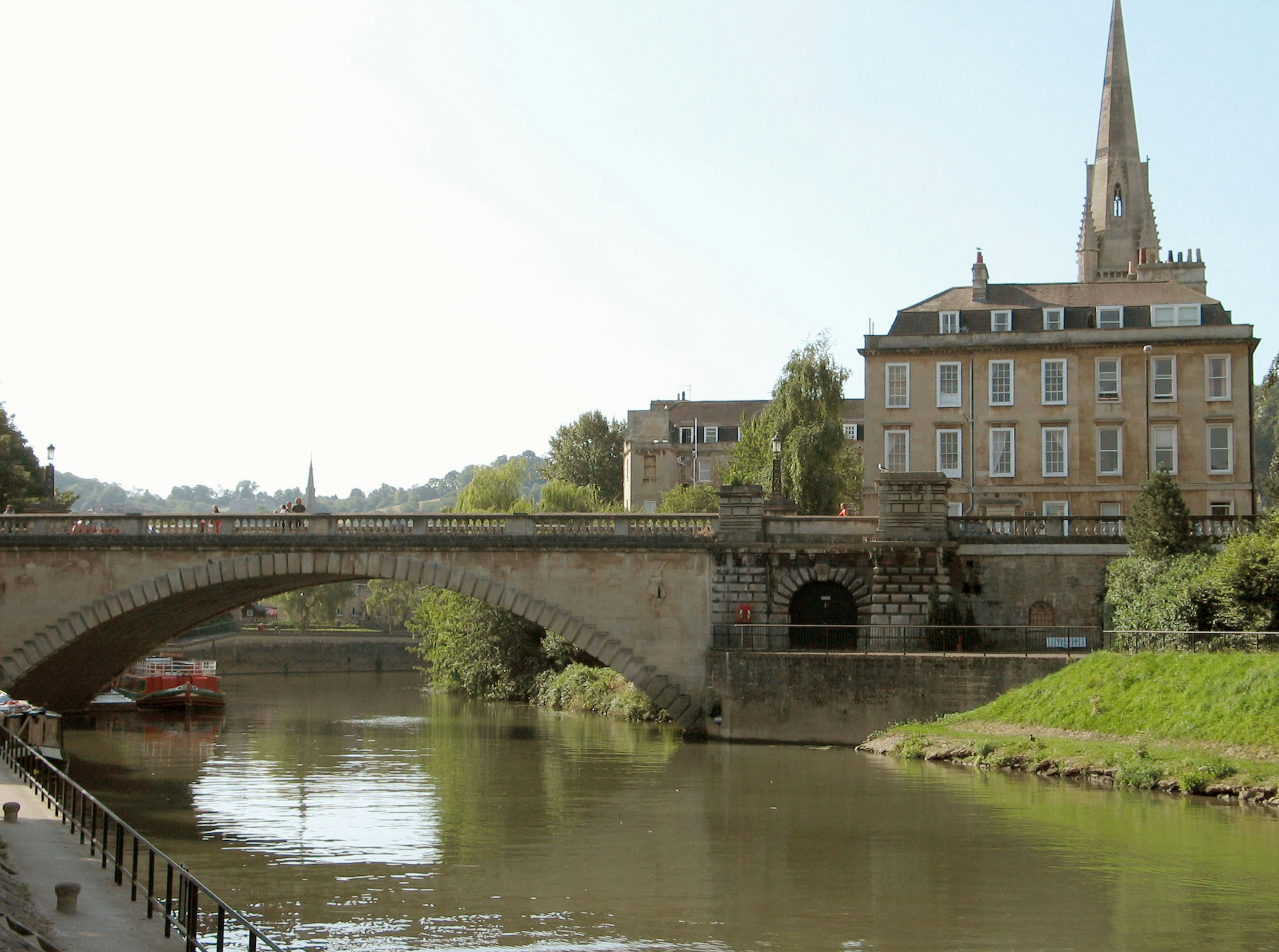 Scenic view featuring a river and an old stone bridge with a church spire in the background