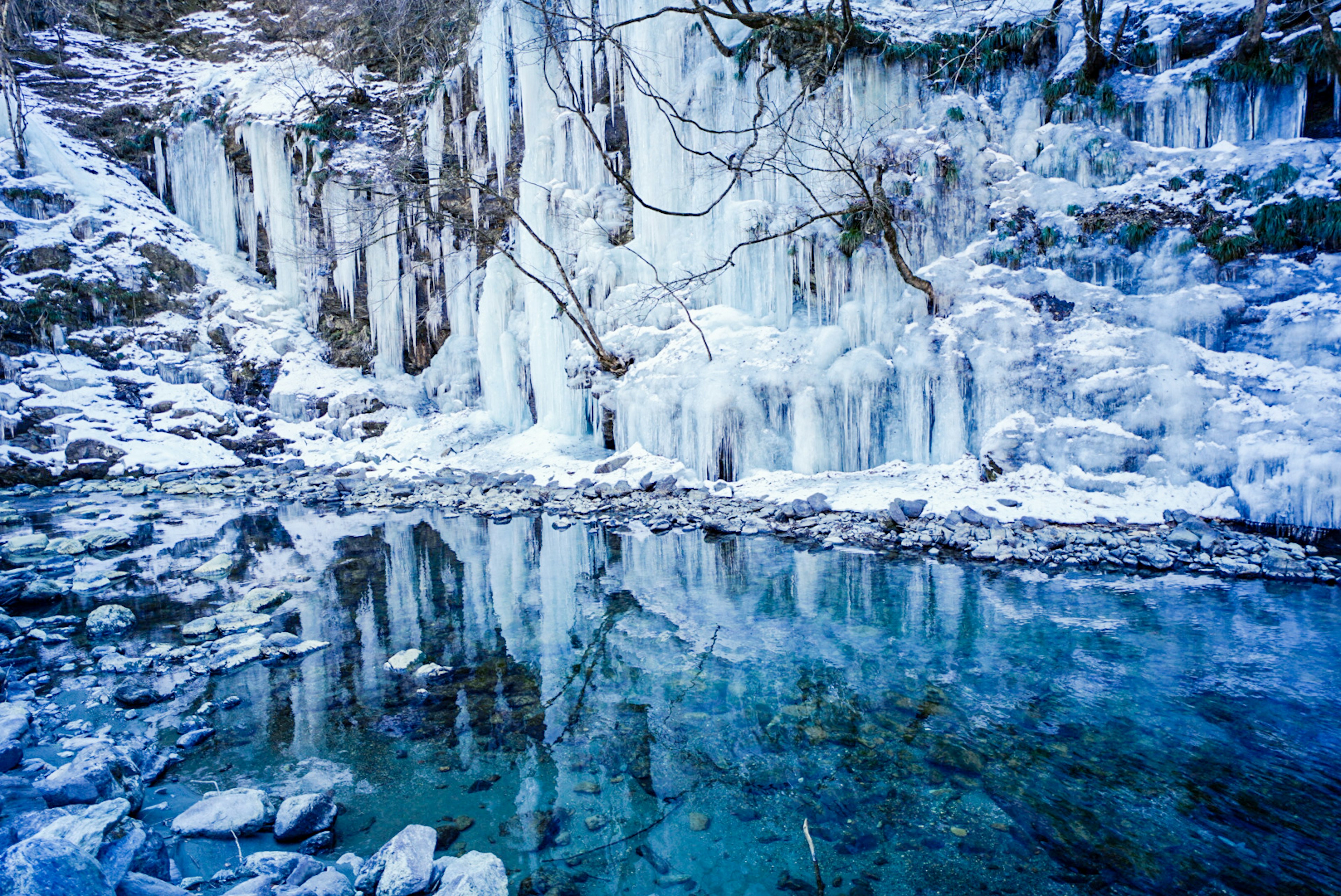 Winter landscape featuring an icy waterfall and a reflective pool