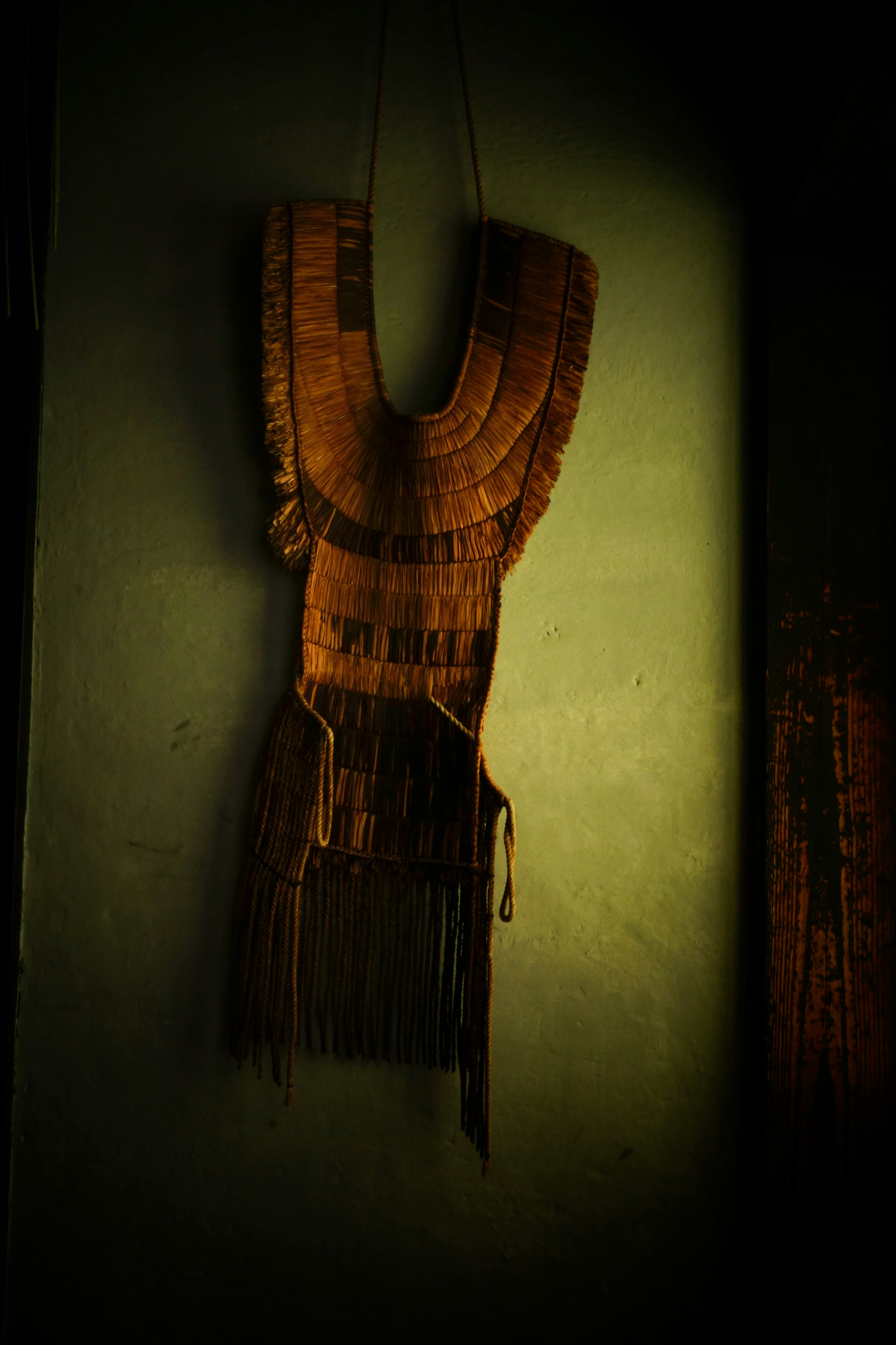 Brown decorative piece with fringes hanging on the wall